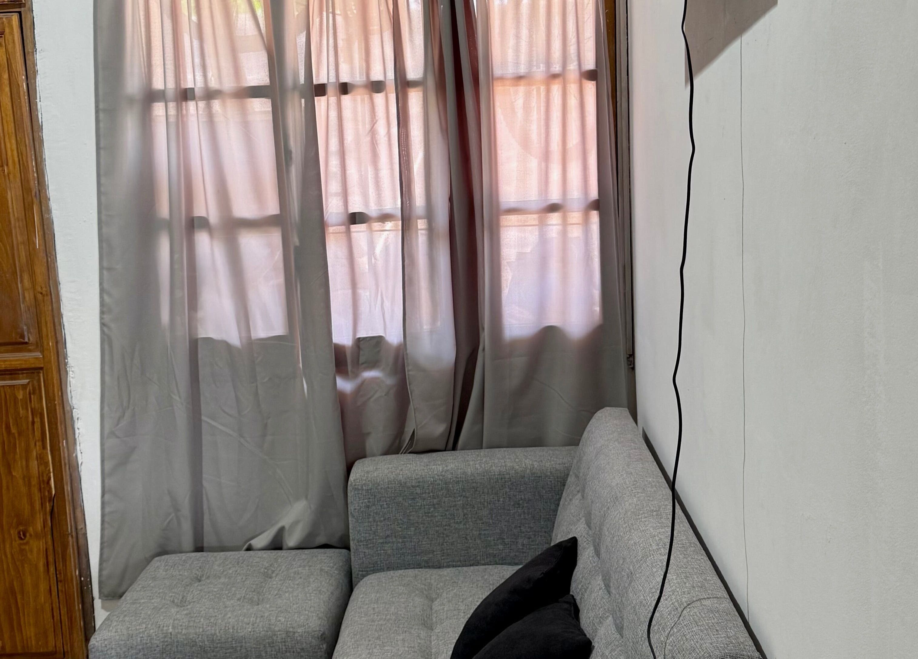 Sala de estar luminosa en Almabella, Mendoza, Mendoza, AR con sofá gris y cortinas suaves.