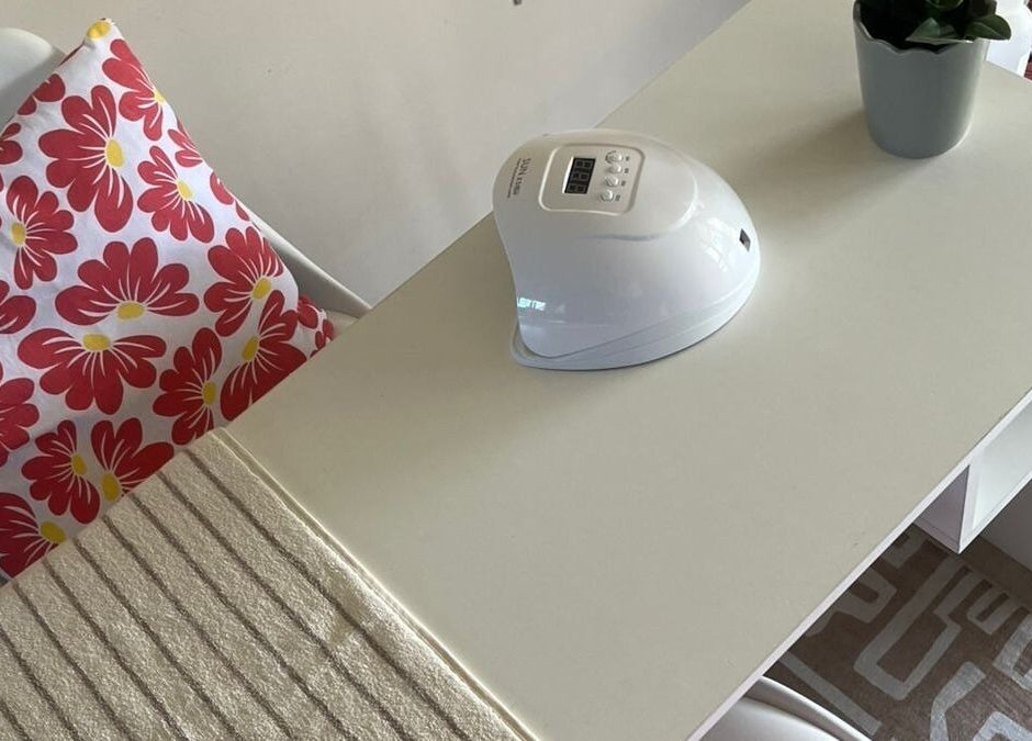 Manicure station at Coastal Pearl, Gqeberha, Eastern Cape, ZA, featuring a floral cushion and UV nail lamp.