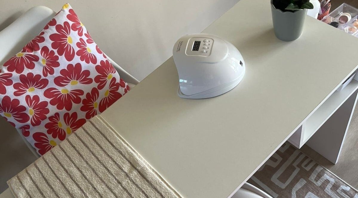 Manicure station at Coastal Pearl, Gqeberha, Eastern Cape, ZA, featuring a floral cushion and UV nail lamp.