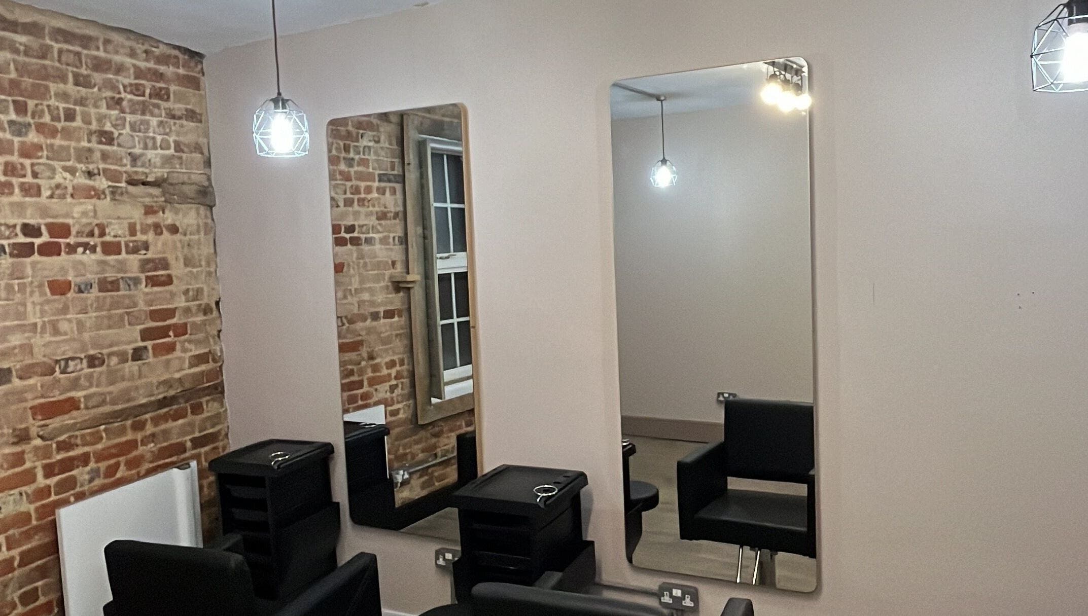 Chic salon interior at The Stockroom, Henlow, England, GB featuring stylish mirrors and exposed brick walls.