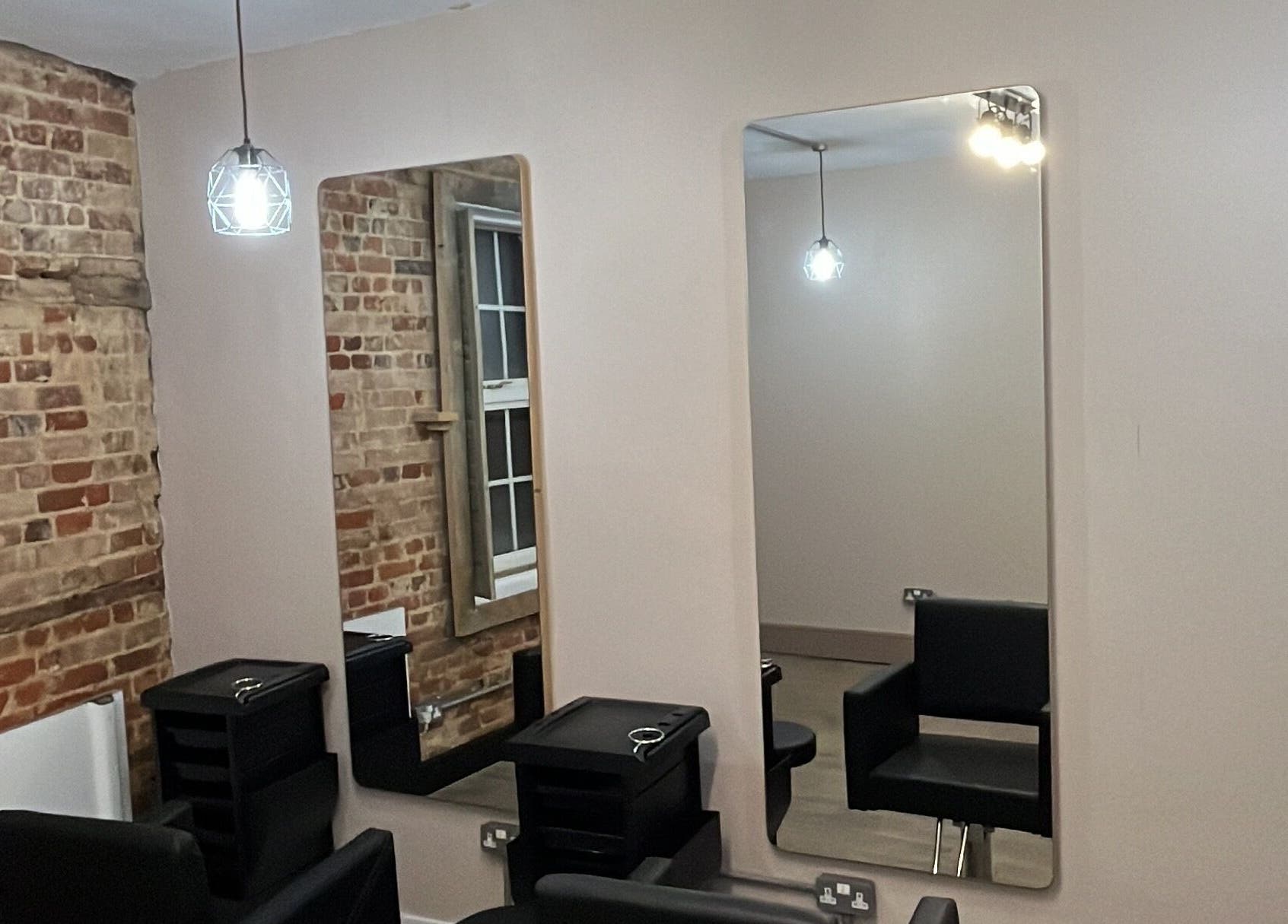Chic salon interior at The Stockroom, Henlow, England, GB featuring stylish mirrors and exposed brick walls.