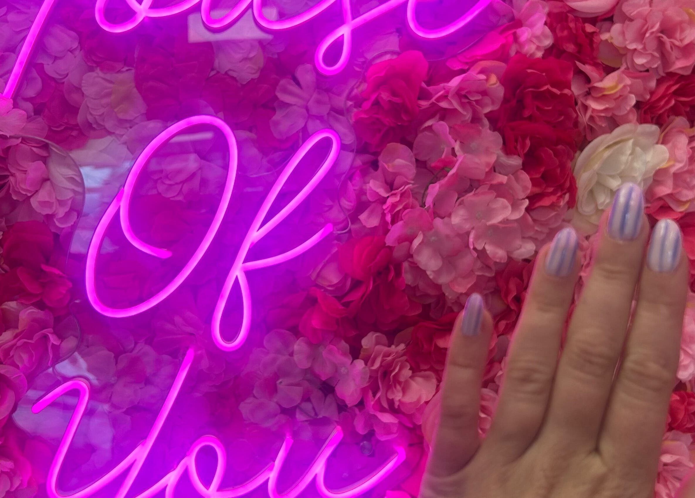 Stylish nails at The Nail Rituals in Exeter, England, GB with vibrant pink neon and floral background.