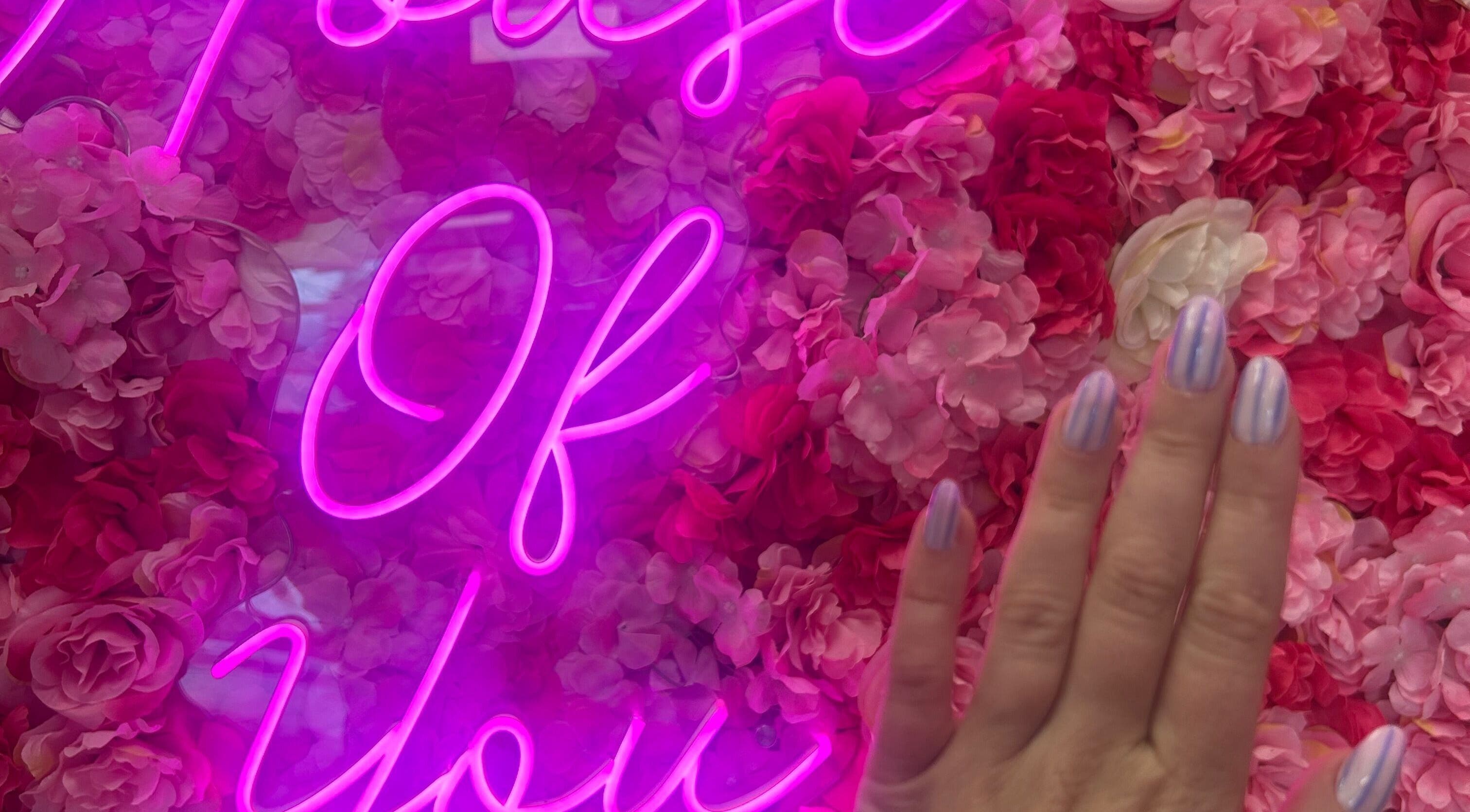 Stylish nails at The Nail Rituals in Exeter, England, GB with vibrant pink neon and floral background.