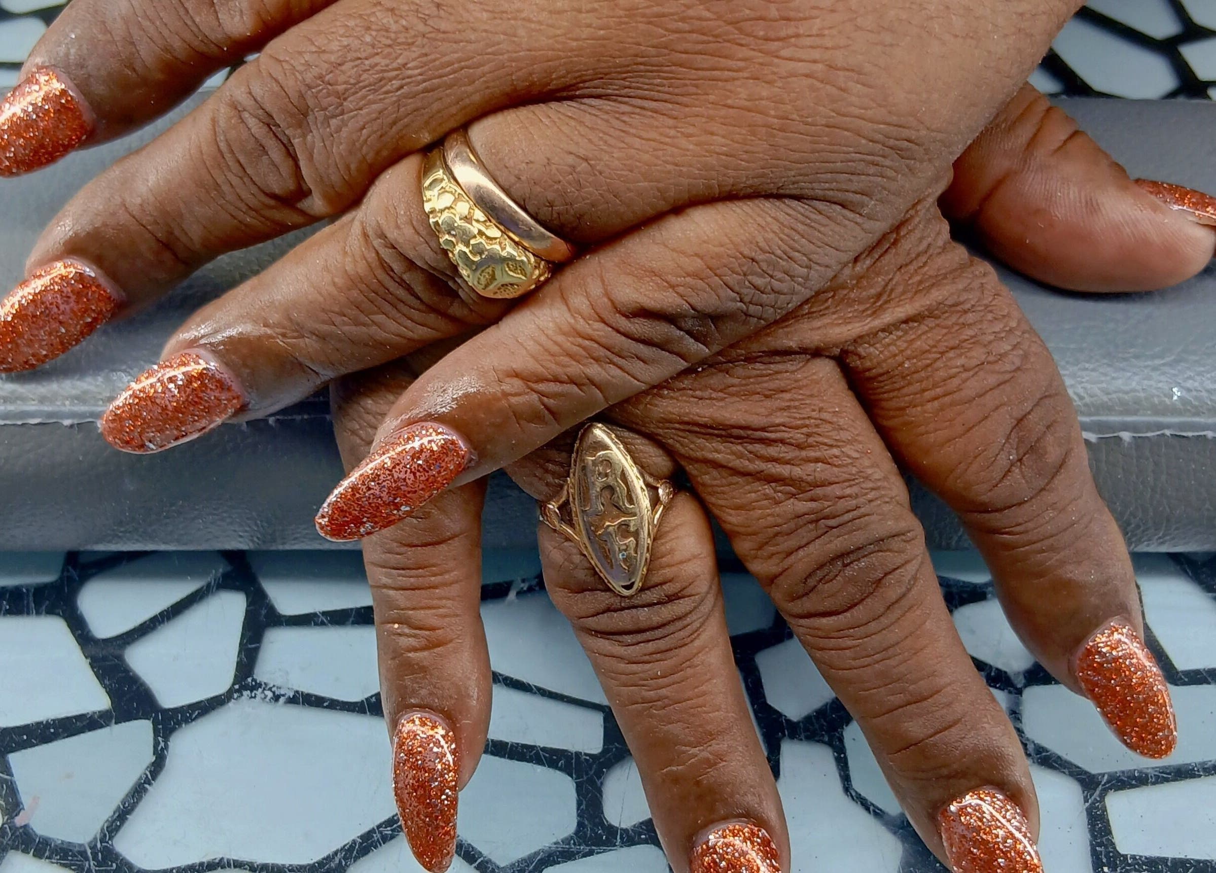 Glittering orange nails with gold rings at Golden Phoenix Nails in Koolbaai, Sint Maarten, SX.