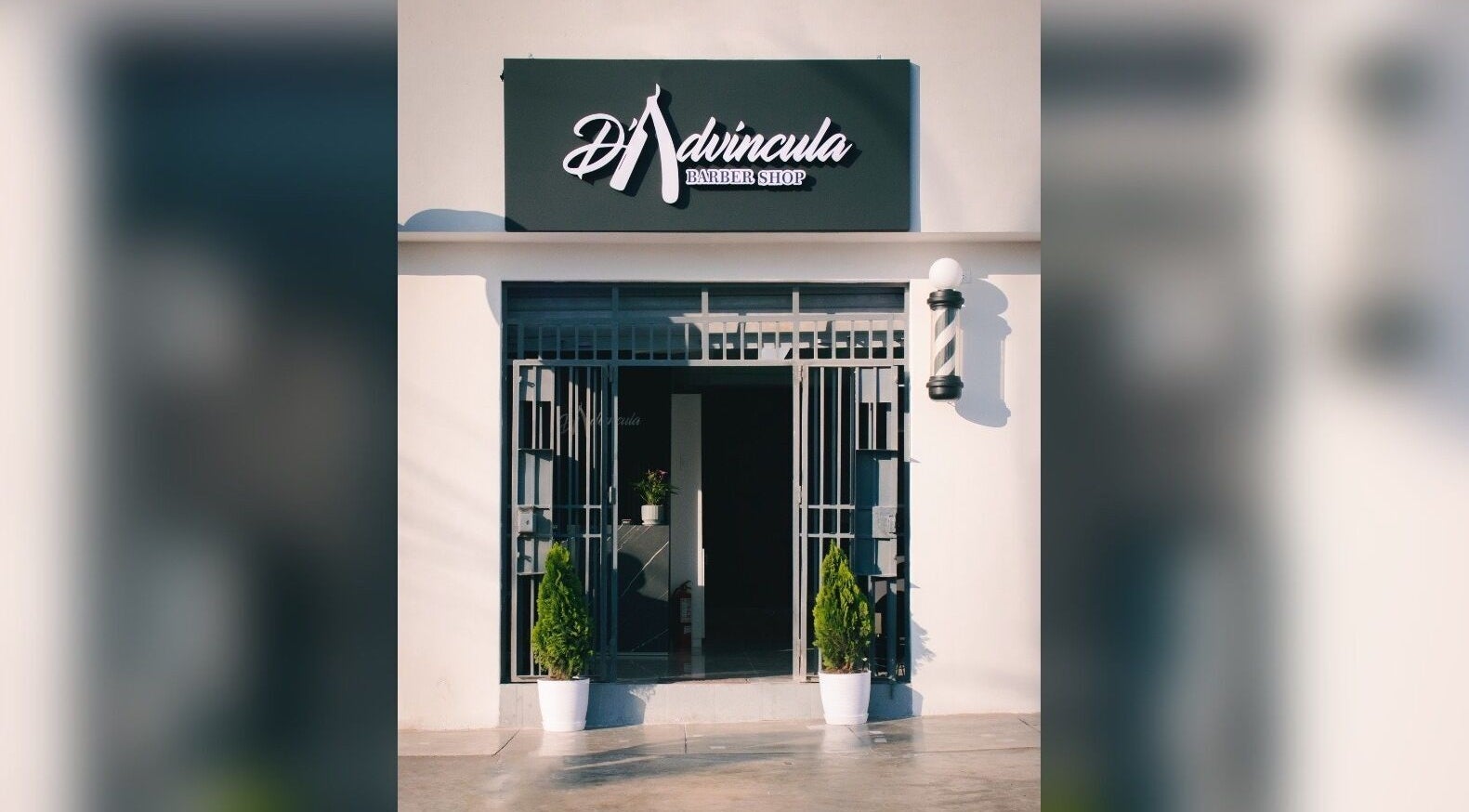Entrada de D' Advincula Barbershop en San Juan De Miraflores, Provincia De Lima, PE, con plantas decorativas.