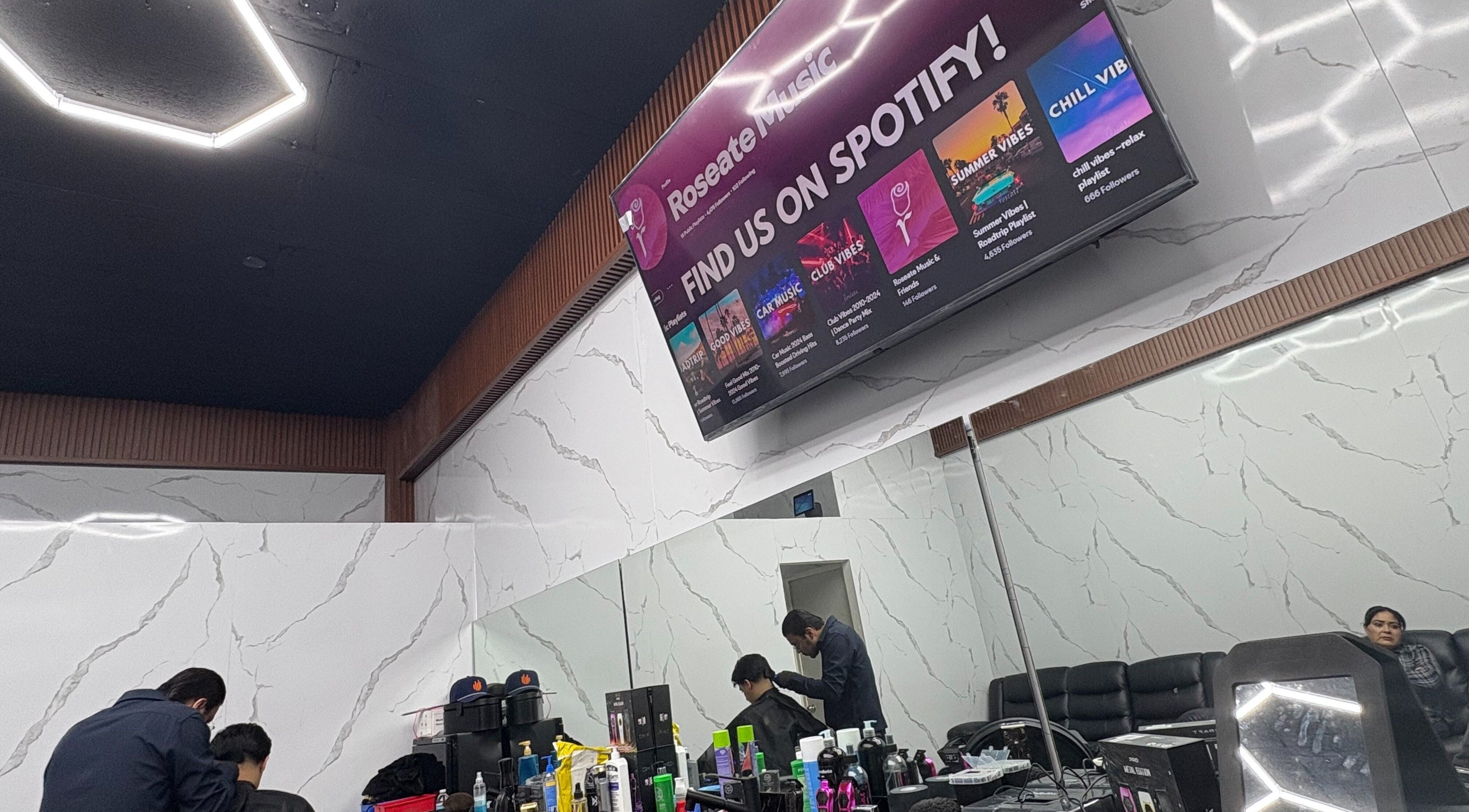 Interior moderno de Barberia Del Patron en Hermosillo, Sonora, MX con pantalla promocional.