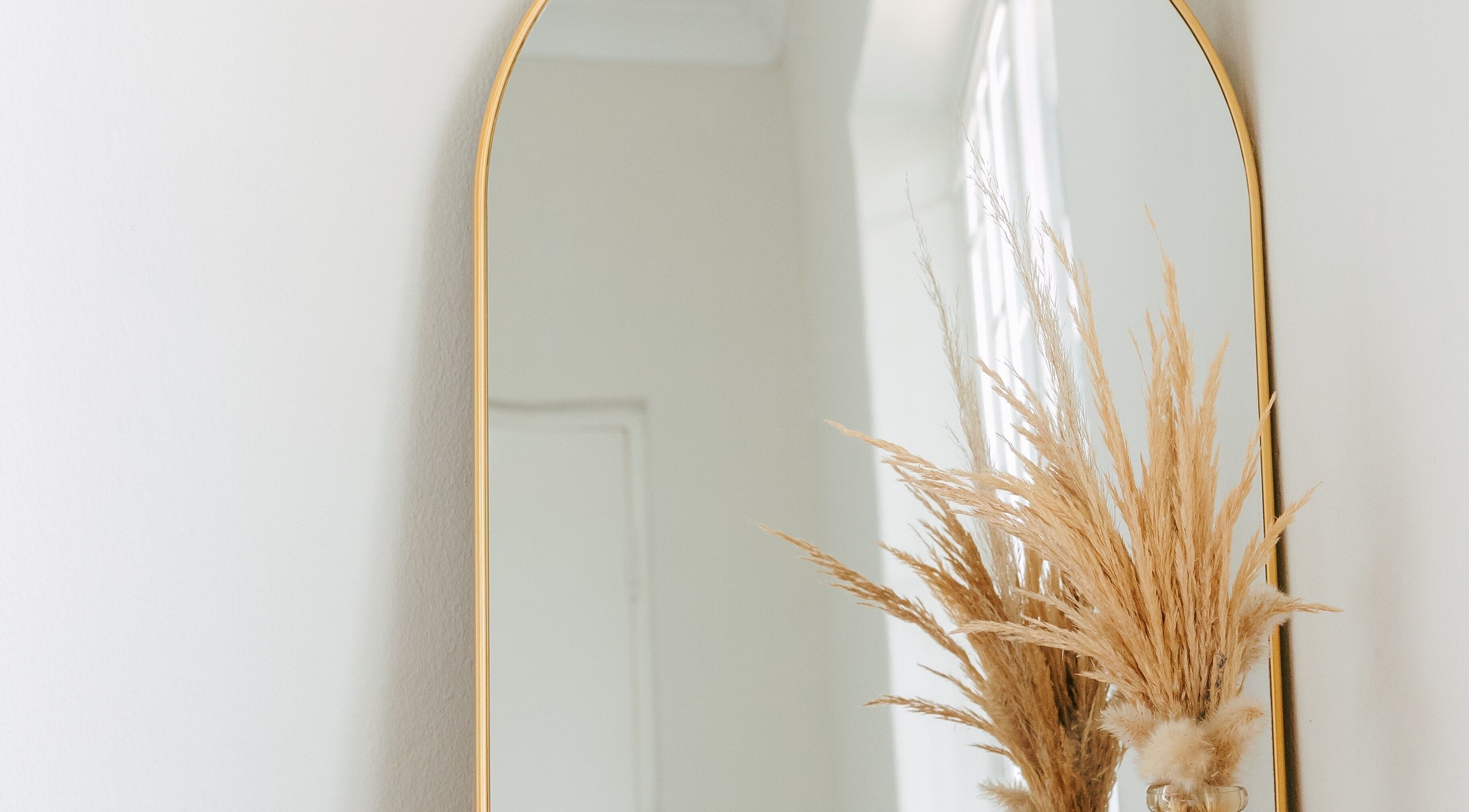 Gold-rimmed mirror at Heath Chromatic, Pretoria, Gauteng, ZA featuring pampas grass decor.