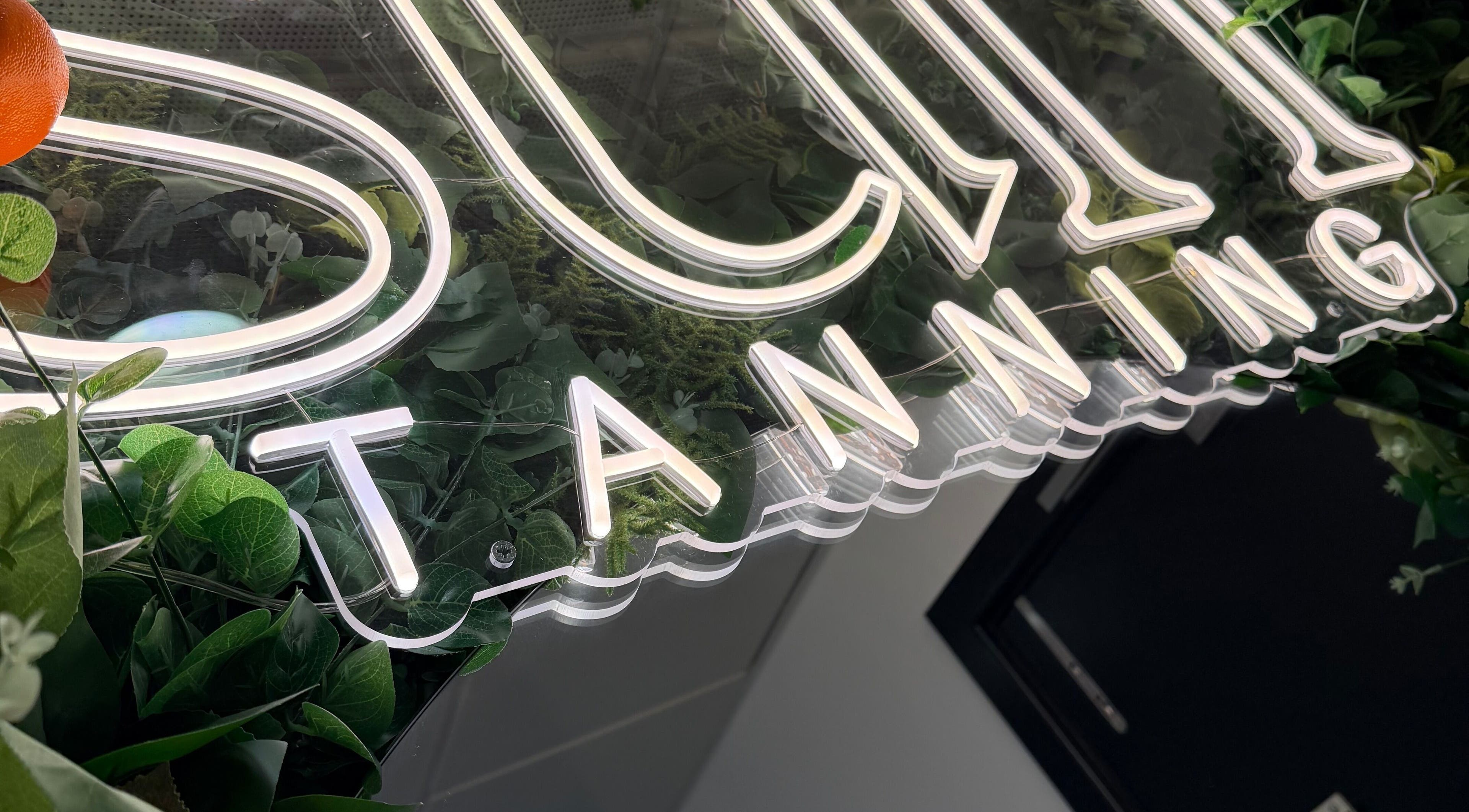 Studio Amy sign with neon glow surrounded by lush greenery in Chester-le-Street, England, GB.