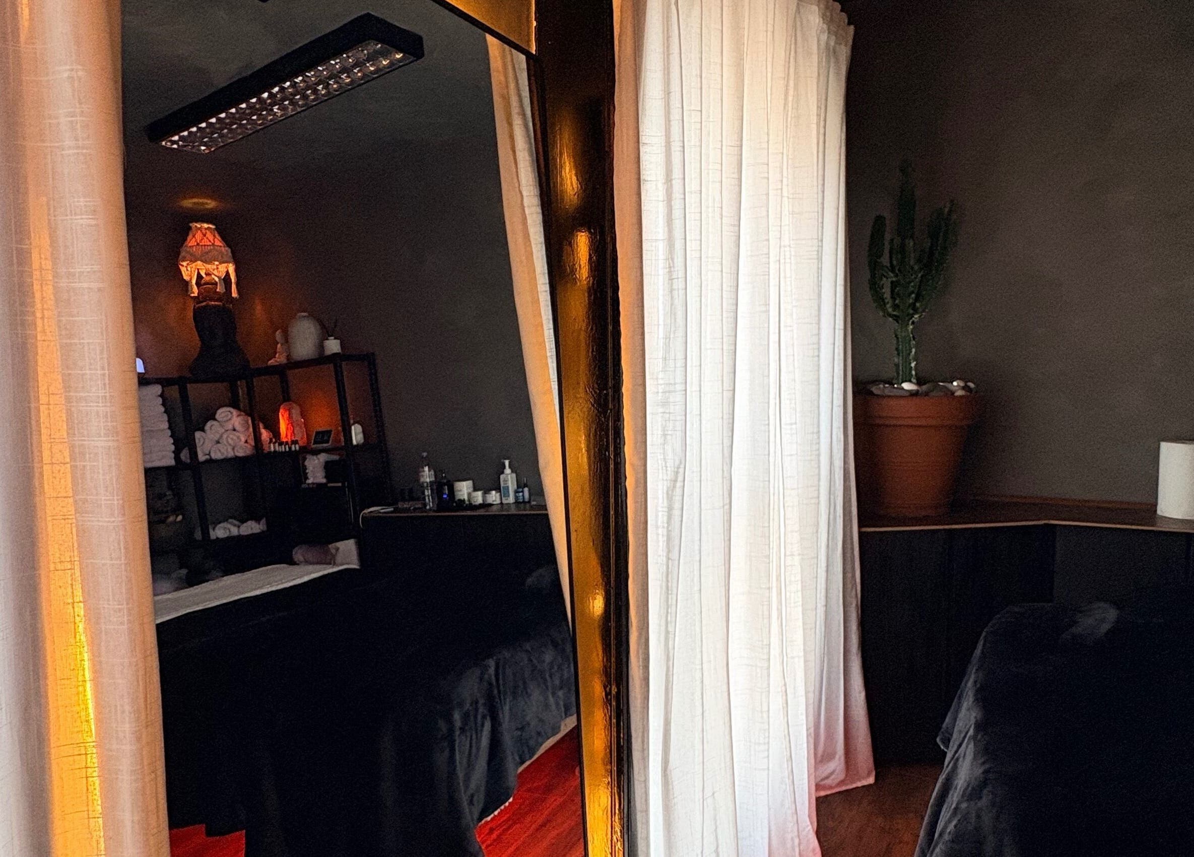 Cozy massage room at N a n d o | Massage Therapy, Dalkey, County Dublin, IE with warm lighting and curtains.