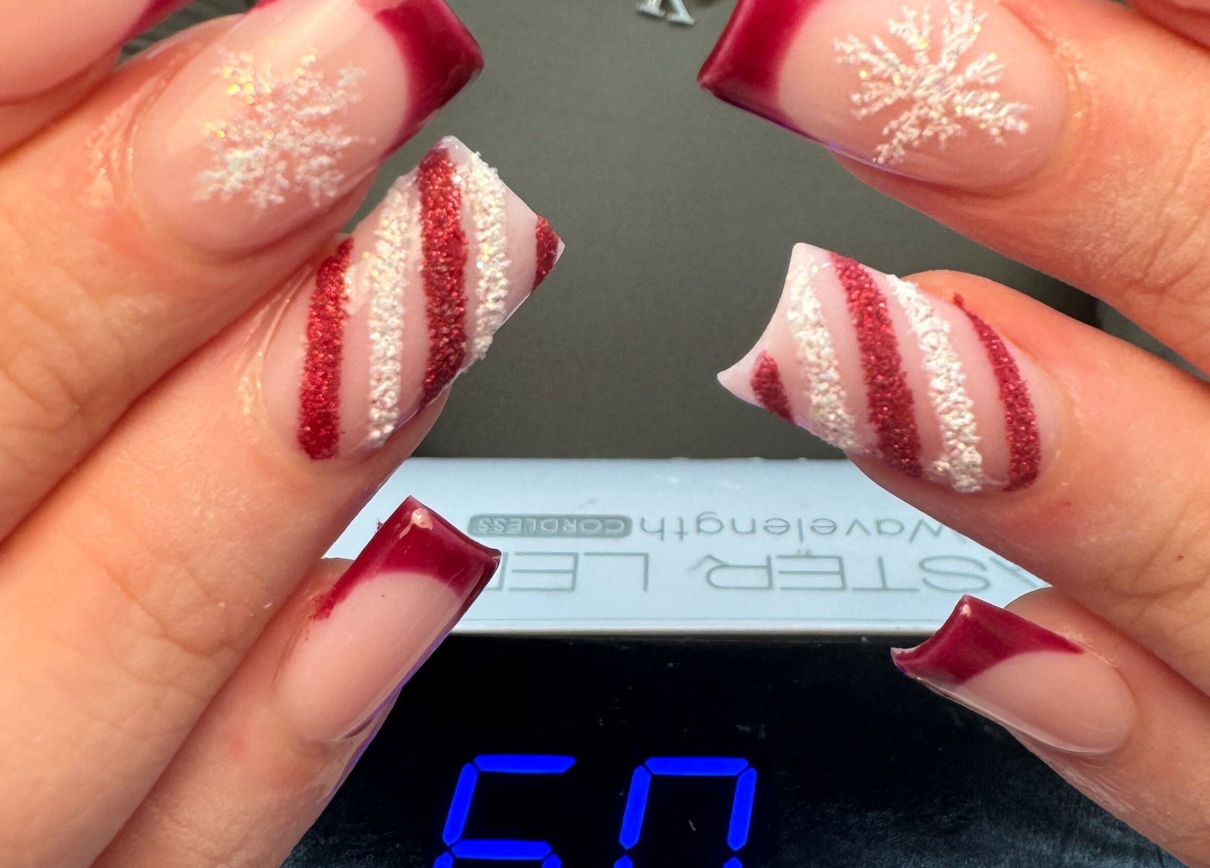 Mẫu móng tay nghệ thuật với họa tiết tuyết và sọc đỏ tại Natural Nail, Birmingham, England, GB.