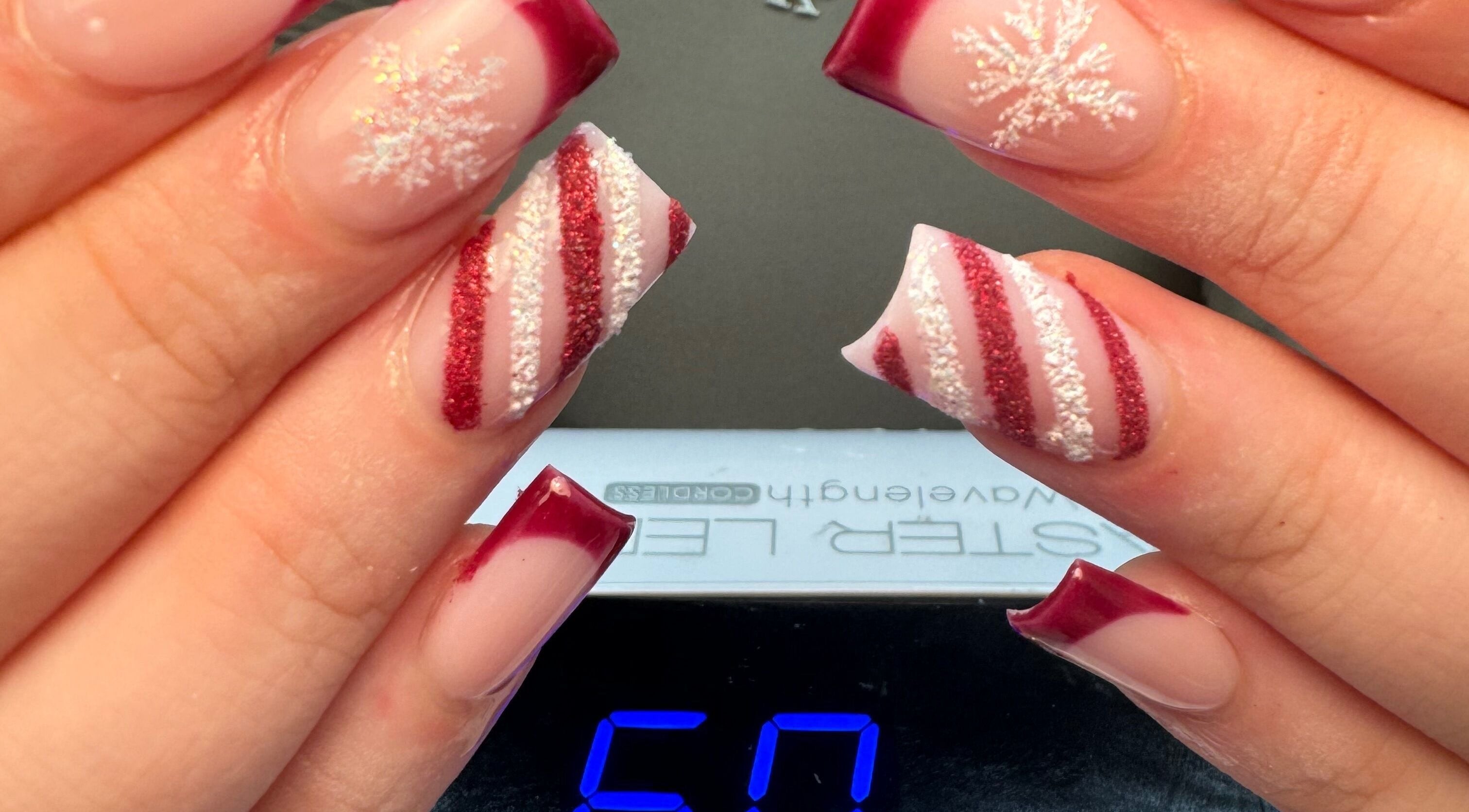 Mẫu móng tay nghệ thuật với họa tiết tuyết và sọc đỏ tại Natural Nail, Birmingham, England, GB.