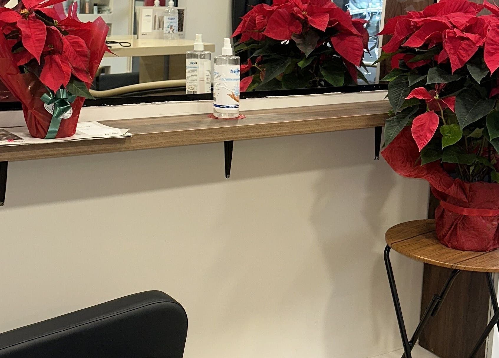 Potted red poinsettias on a shelf at Eri hair&style, Kesariani, GR, adding a festive touch.
