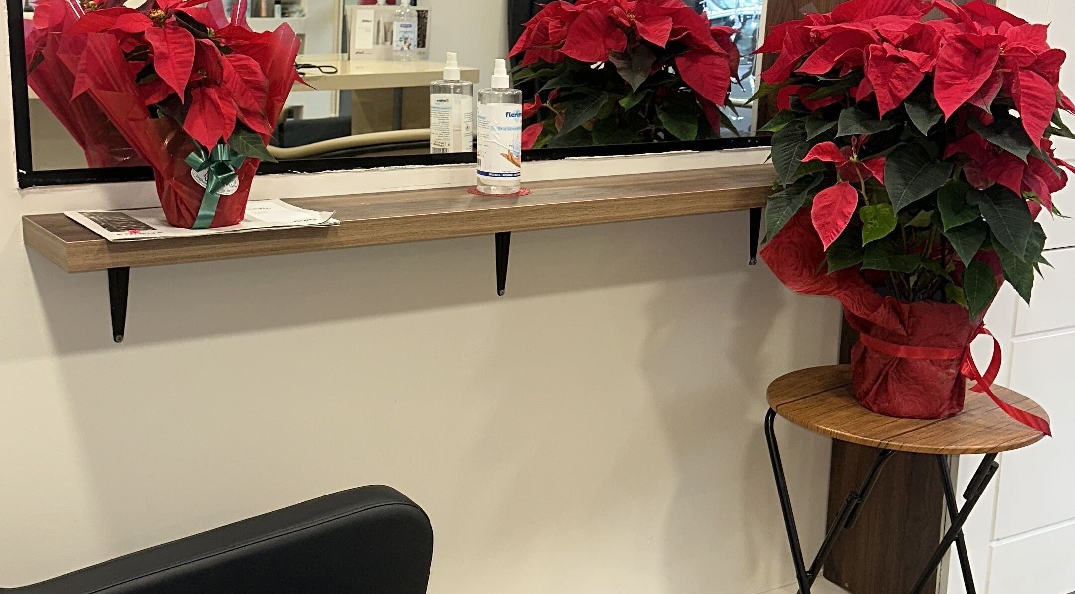 Potted red poinsettias on a shelf at Eri hair&style, Kesariani, GR, adding a festive touch.