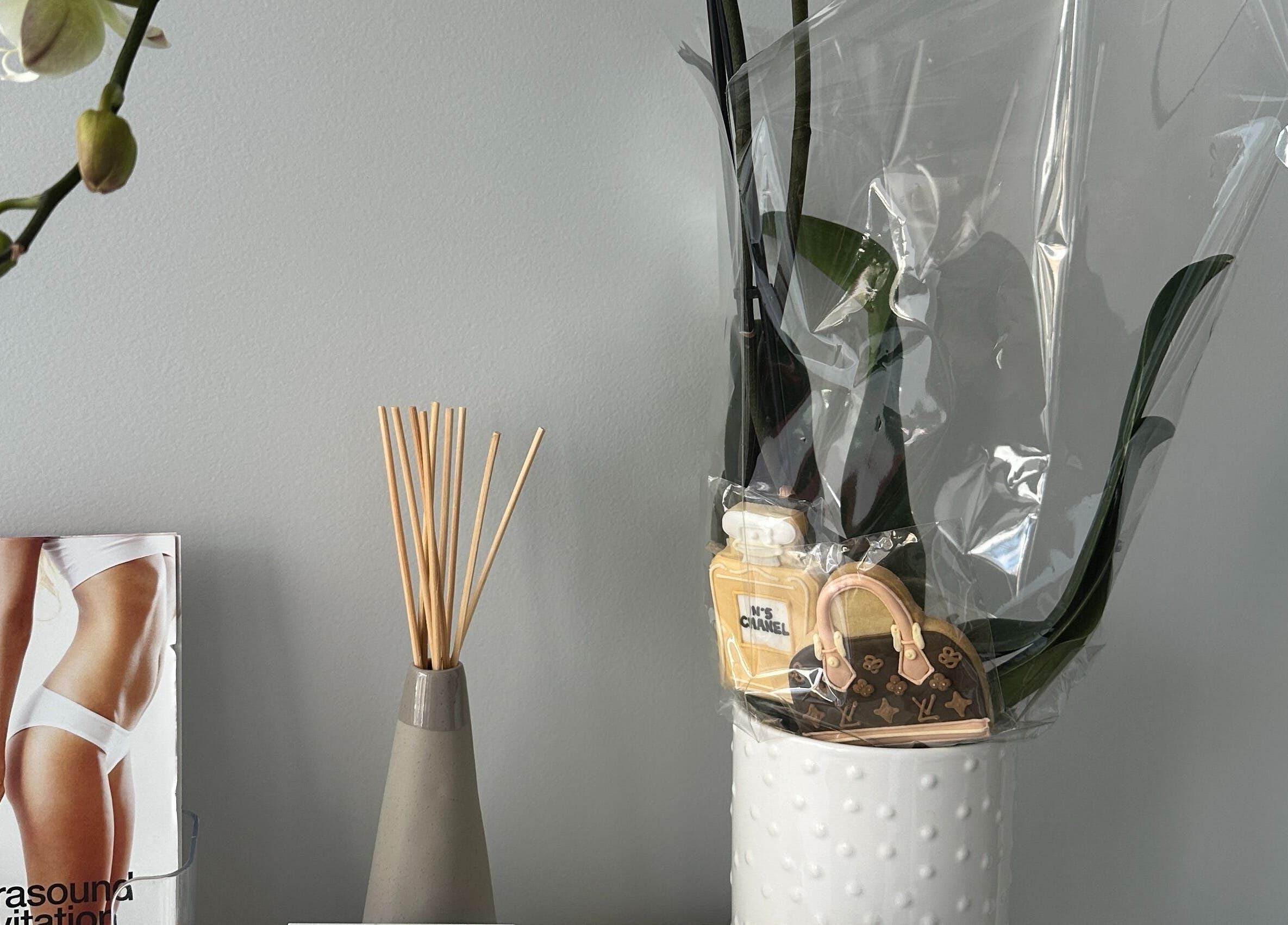 Spa decor at Beauty One Aesthetics, Melbourne, Victoria, AU with a vase, perfume replica, and floral arrangement.