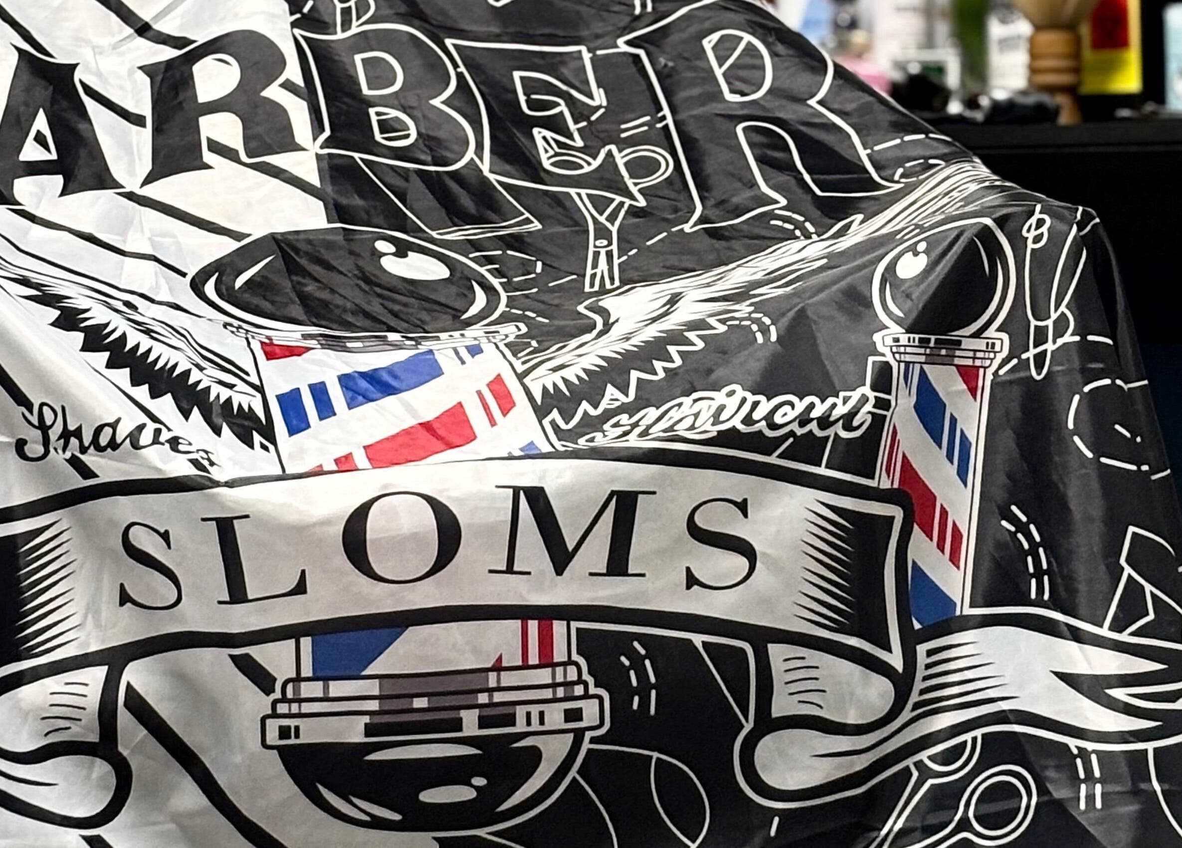 Stylish barber cape at La Bar.bière in Saint-cyrille-de-lessard, Québec, CA showcasing classic salon motifs.