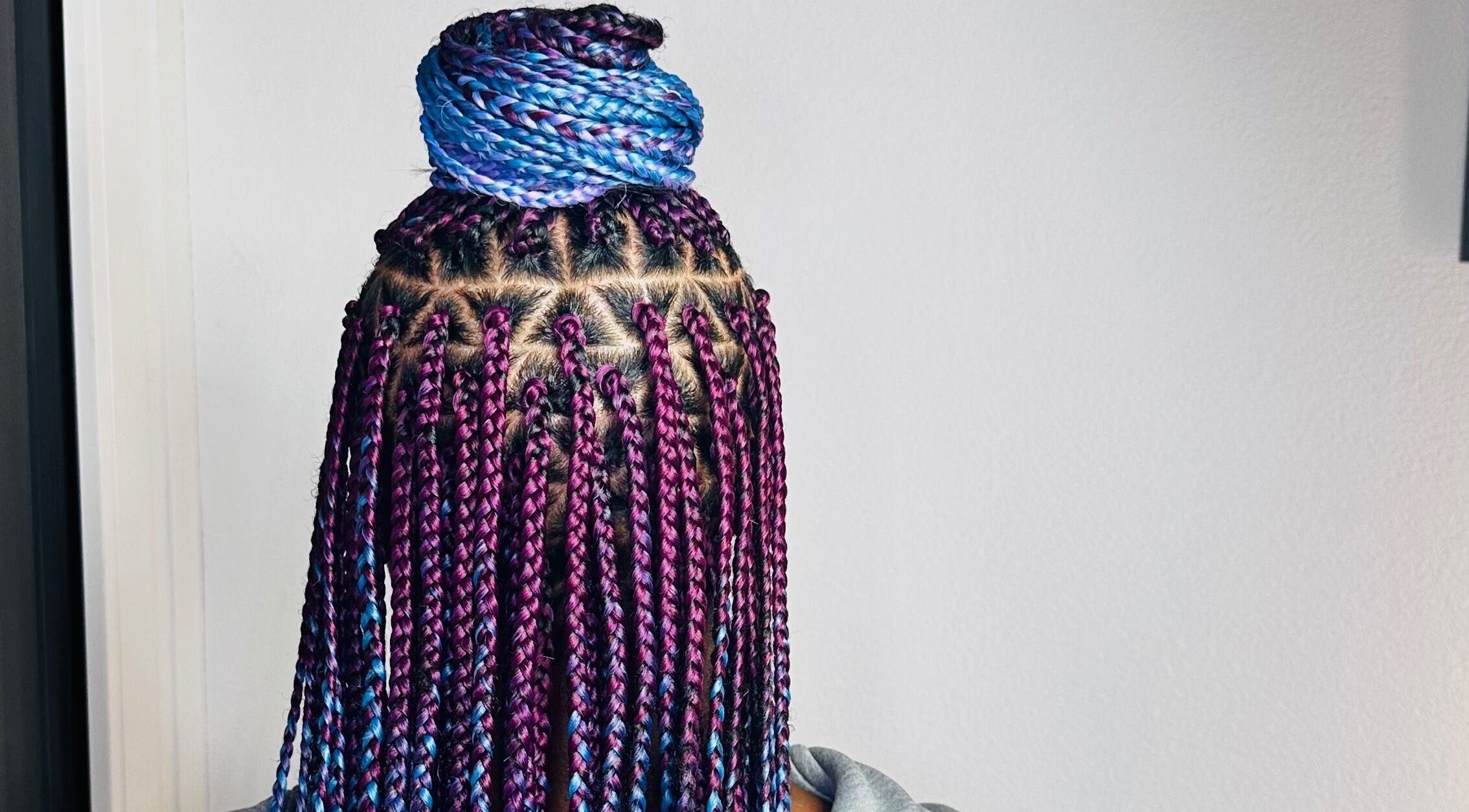 Vibrant braided hairstyle at Braids By Olma in Münsingen, Bern, CH. Purple and blue intricately styled braids.