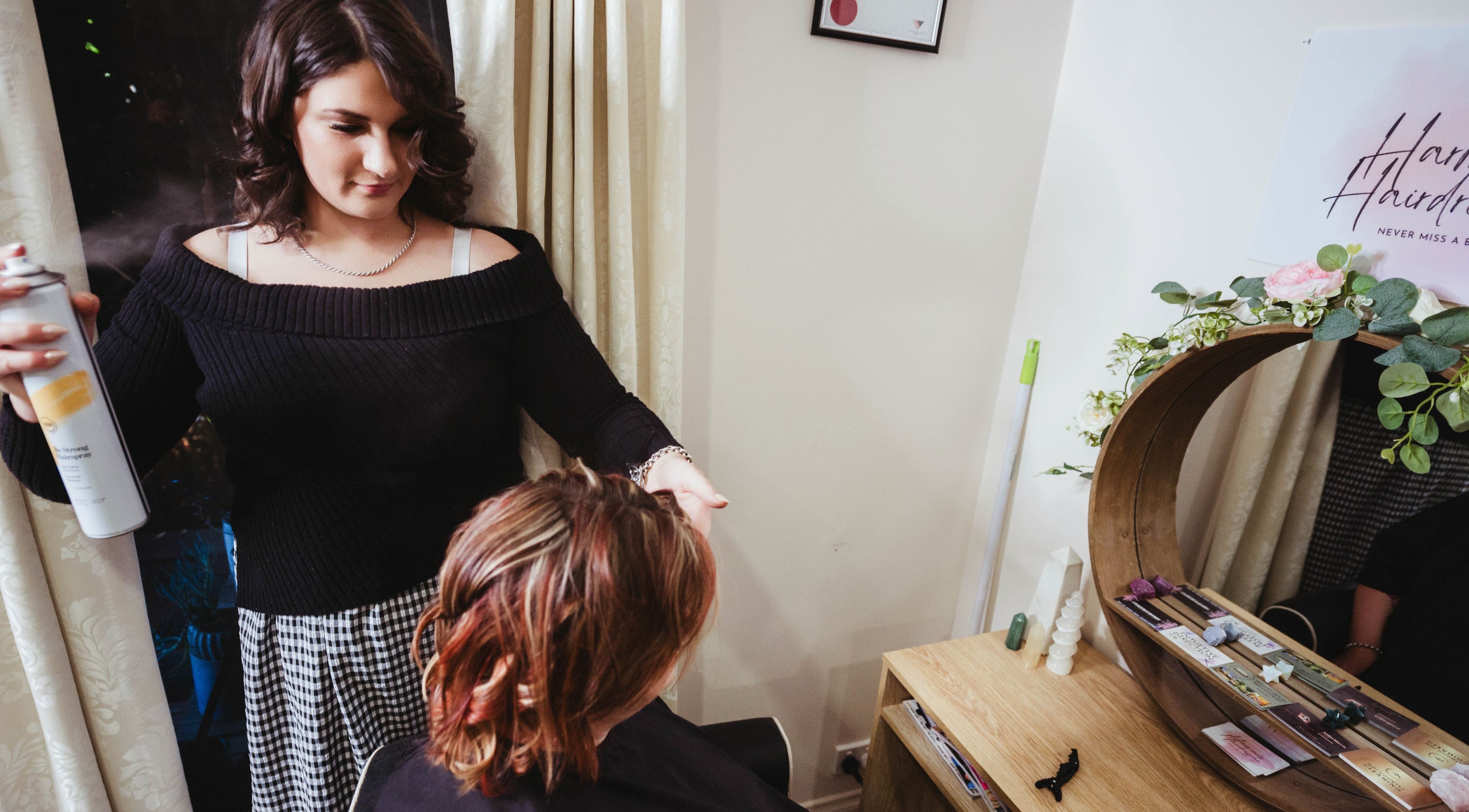 A stylist at Harmonics Hairdressing in Merbein, Victoria, AU, expertly applies hairspray to a client's hair.
