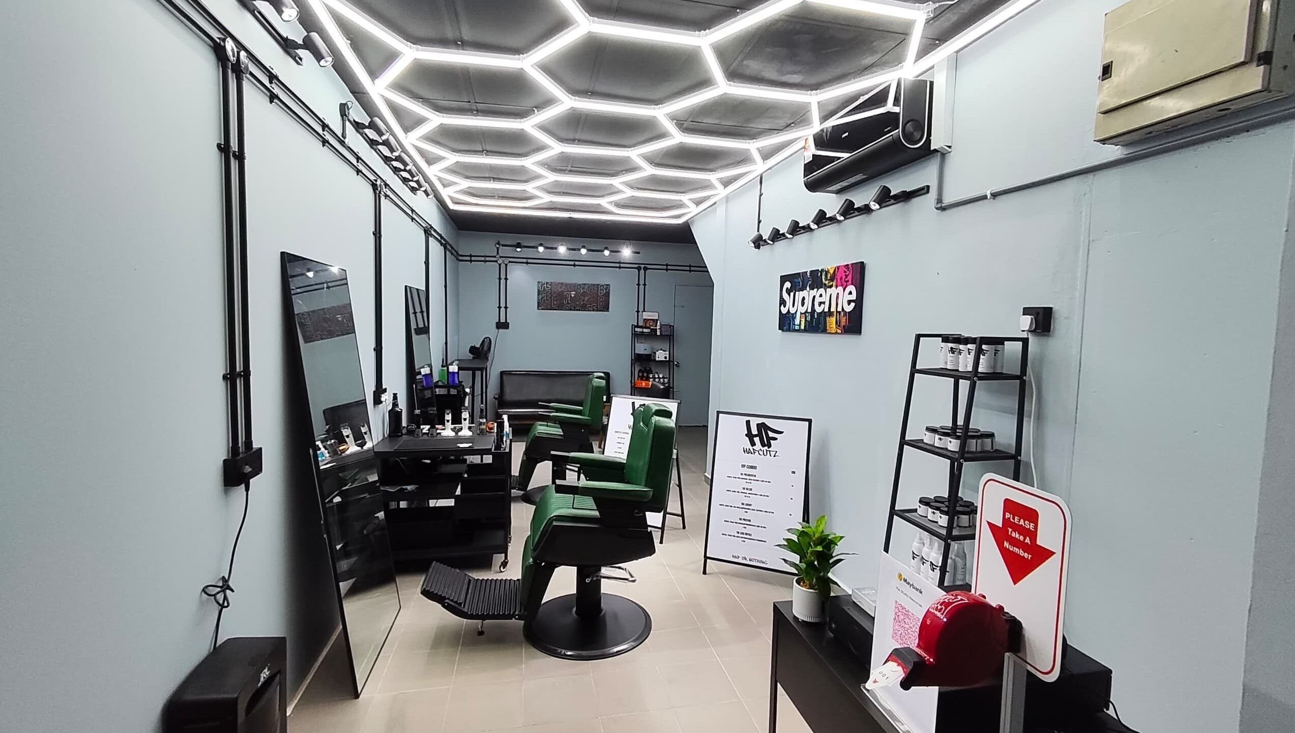 Sleek interior of HAFcutz Barbershop in Johor Bahru, featuring stylish green chairs and modern decor.