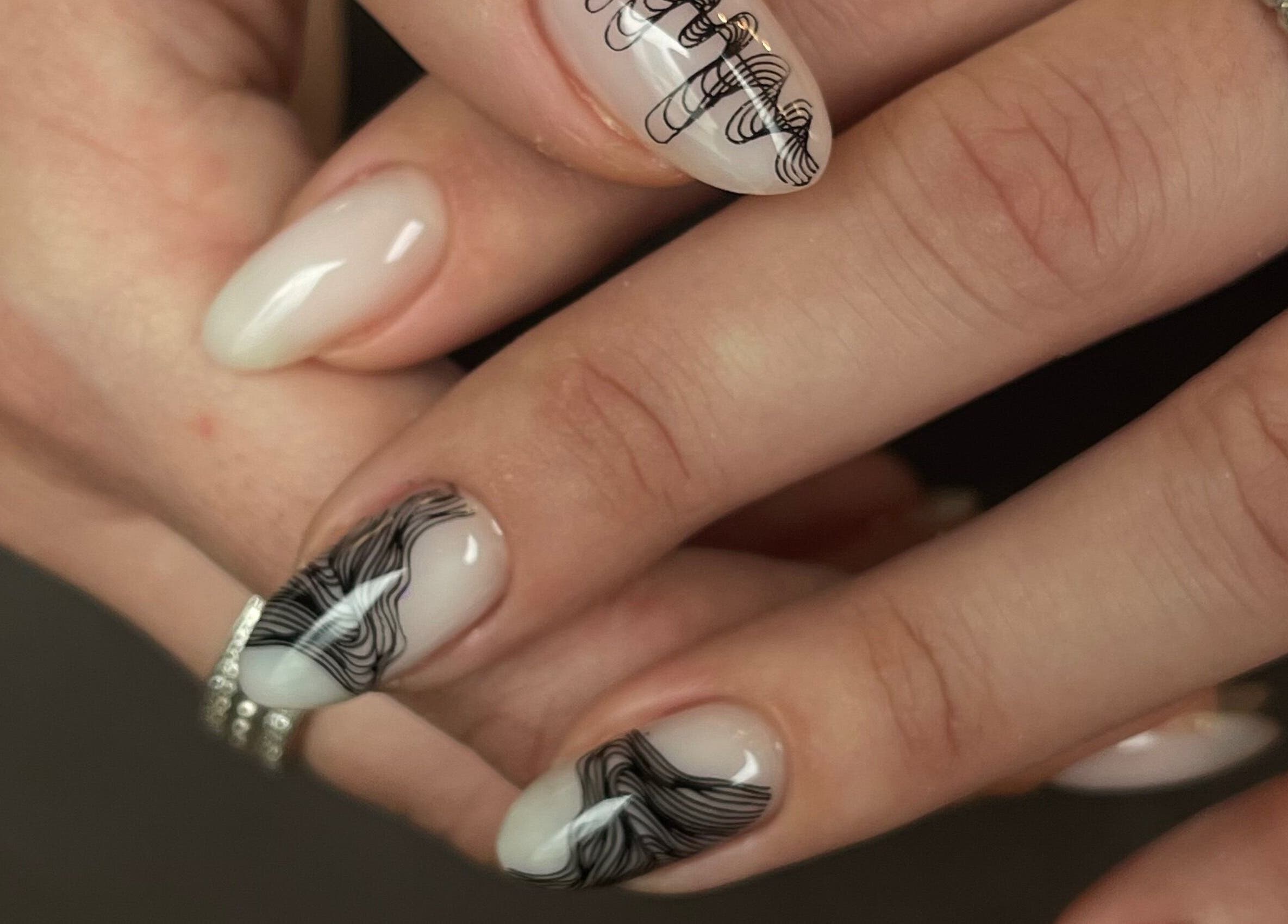 Thiết kế móng nghệ thuật tại Redpetals.studio.hanoi, Hà Nội, Hà Nội, VN, với họa tiết đen tinh tế trên nền trắng.