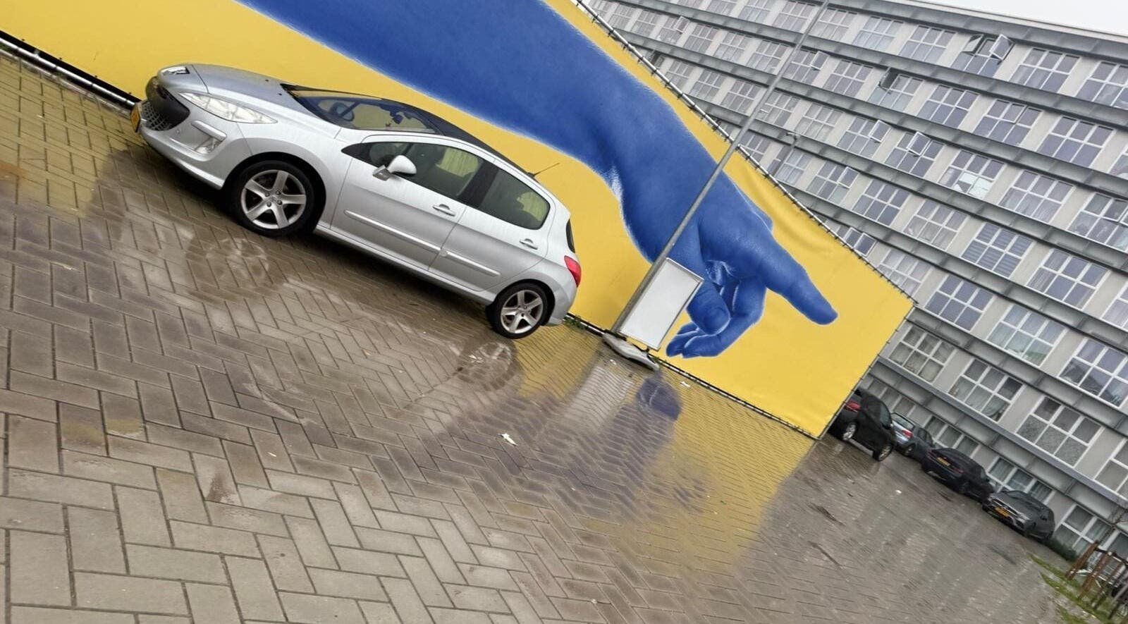 Grijze auto voor blauwe muurschildering nabij Intentionails, Amsterdam, Noord-Holland, NL.