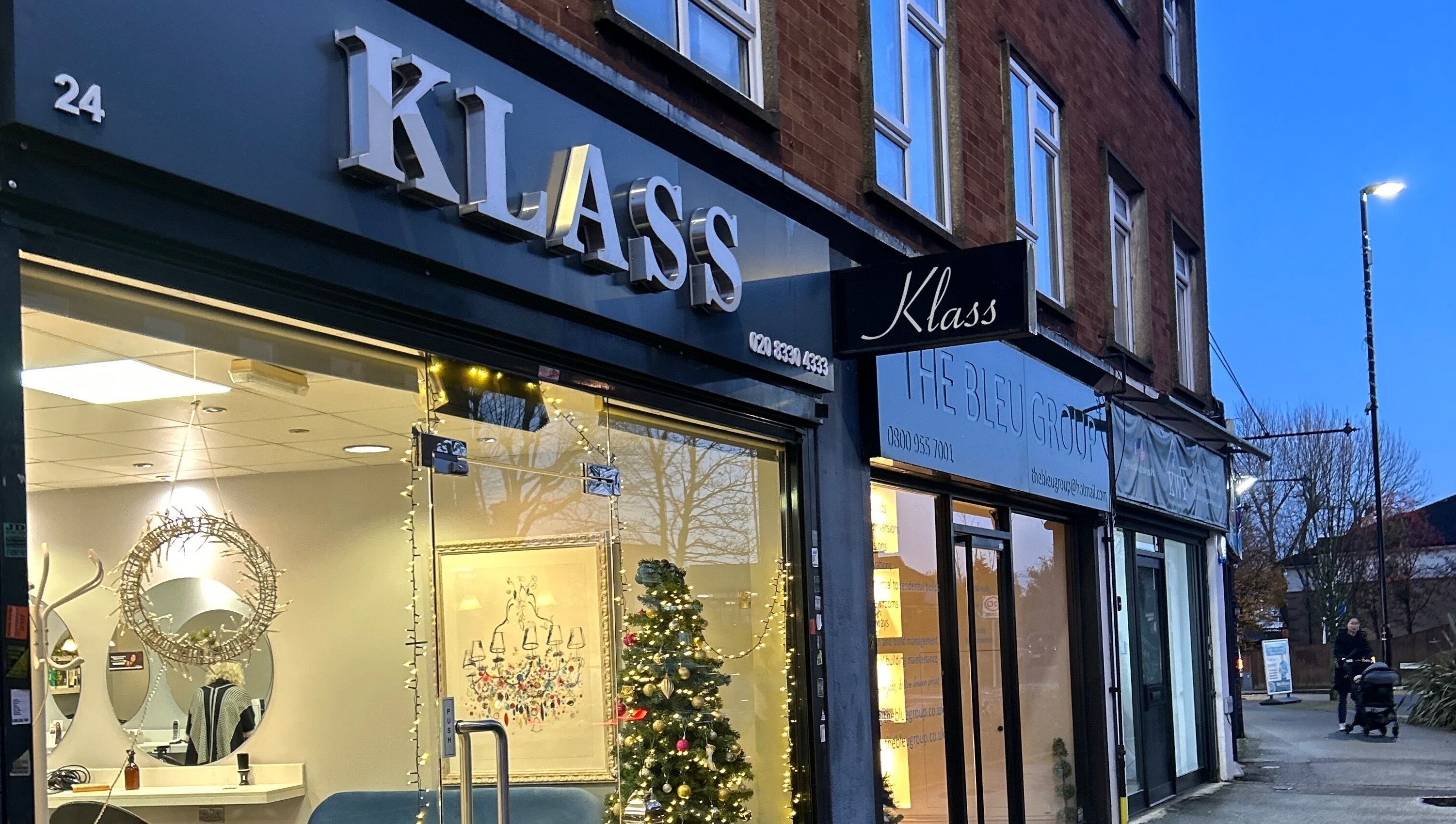 Chic storefront of PGeorgiou - Hairdresser at Worcester Park, England, GB, warmly lit in the evening.