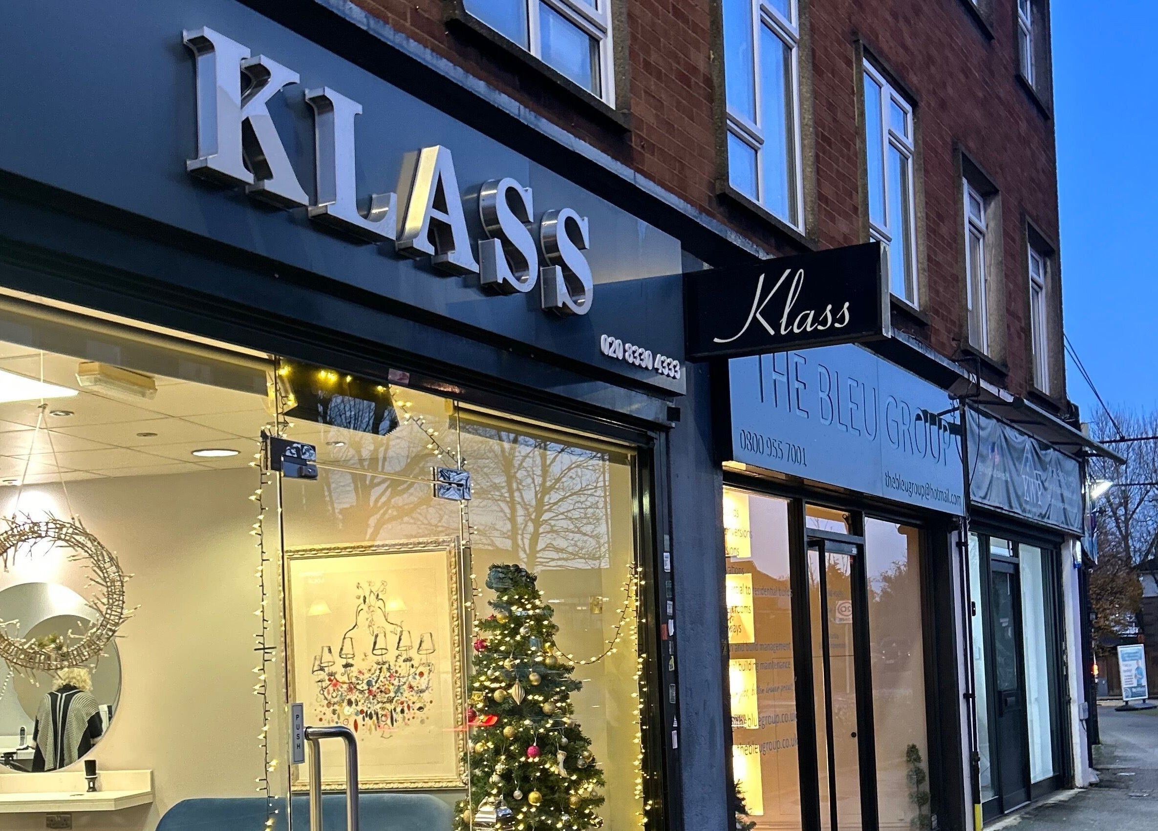Chic storefront of PGeorgiou - Hairdresser at Worcester Park, England, GB, warmly lit in the evening.