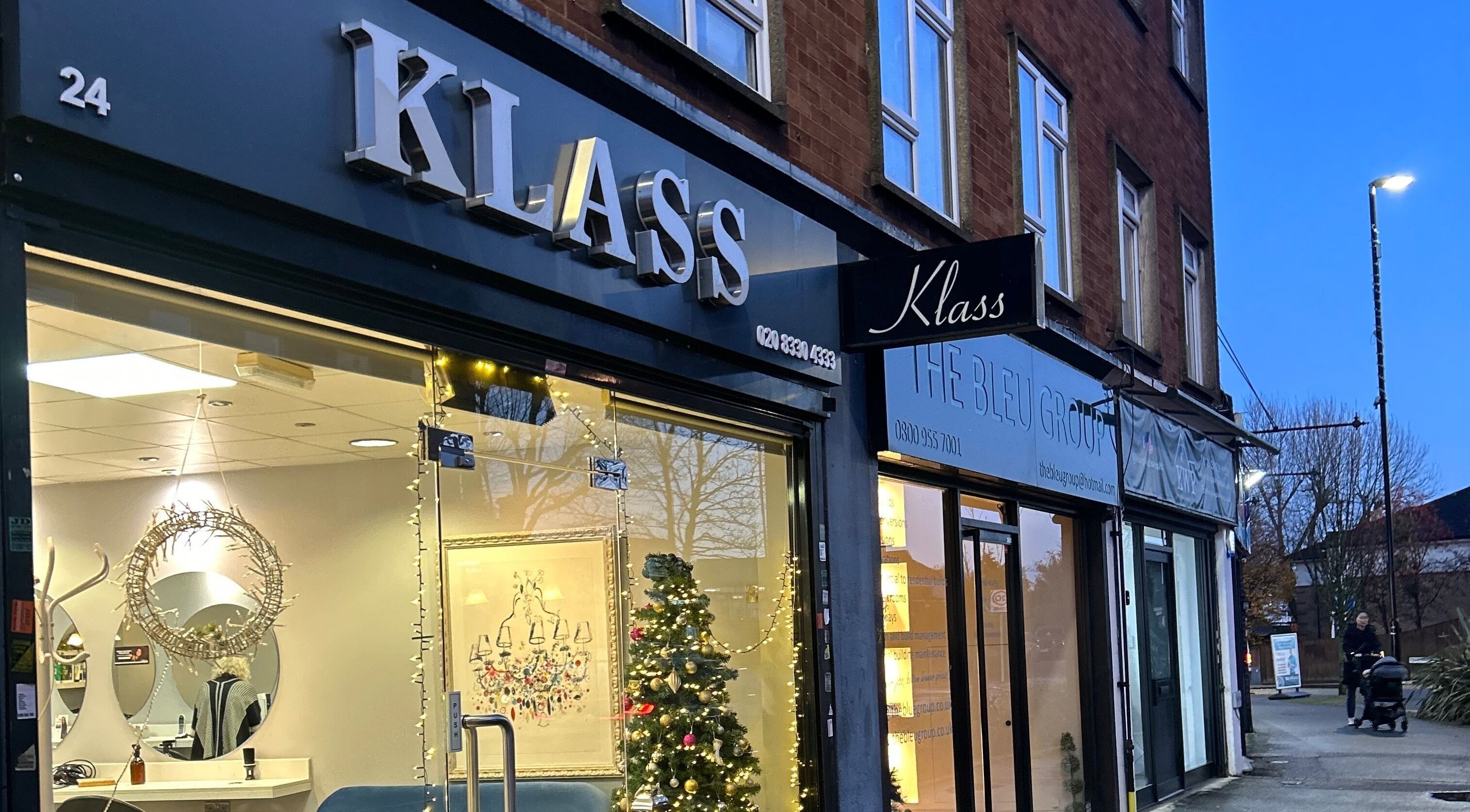 Chic storefront of PGeorgiou - Hairdresser at Worcester Park, England, GB, warmly lit in the evening.