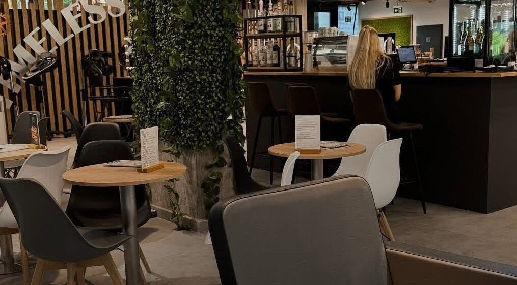 Интерьер кафе в Barber KRVTSV, Hlavní Město Praha, CZ с уютными столиками и зеленью.