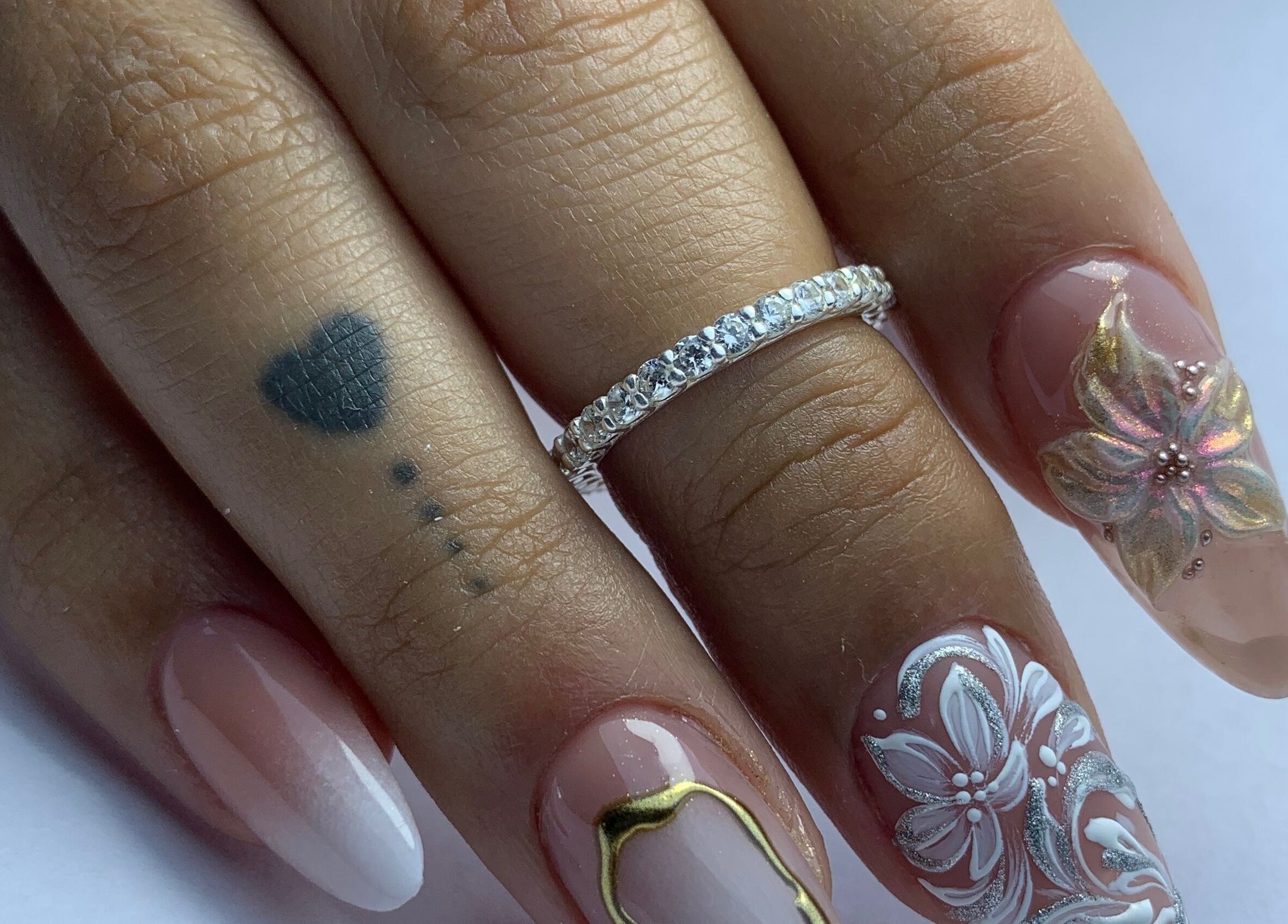 Intricate floral nail art design at Primero las uñas, La Falda, Córdoba, AR with elegant rings.