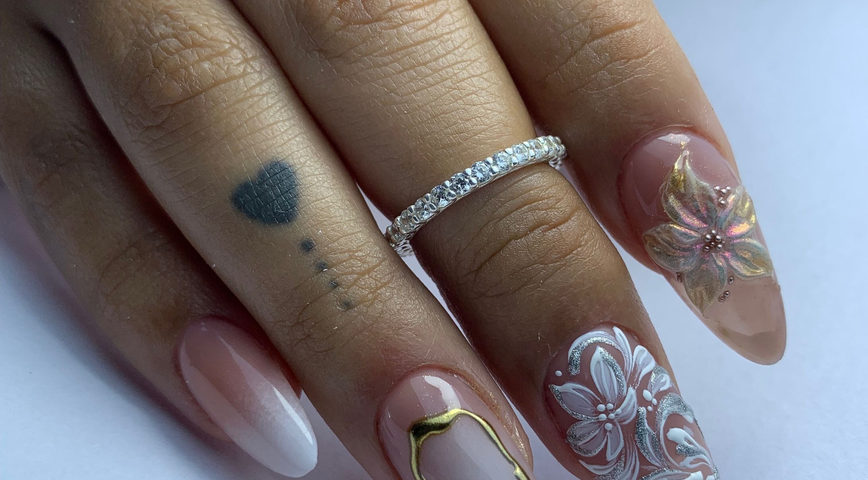 Intricate floral nail art design at Primero las uñas, La Falda, Córdoba, AR with elegant rings.