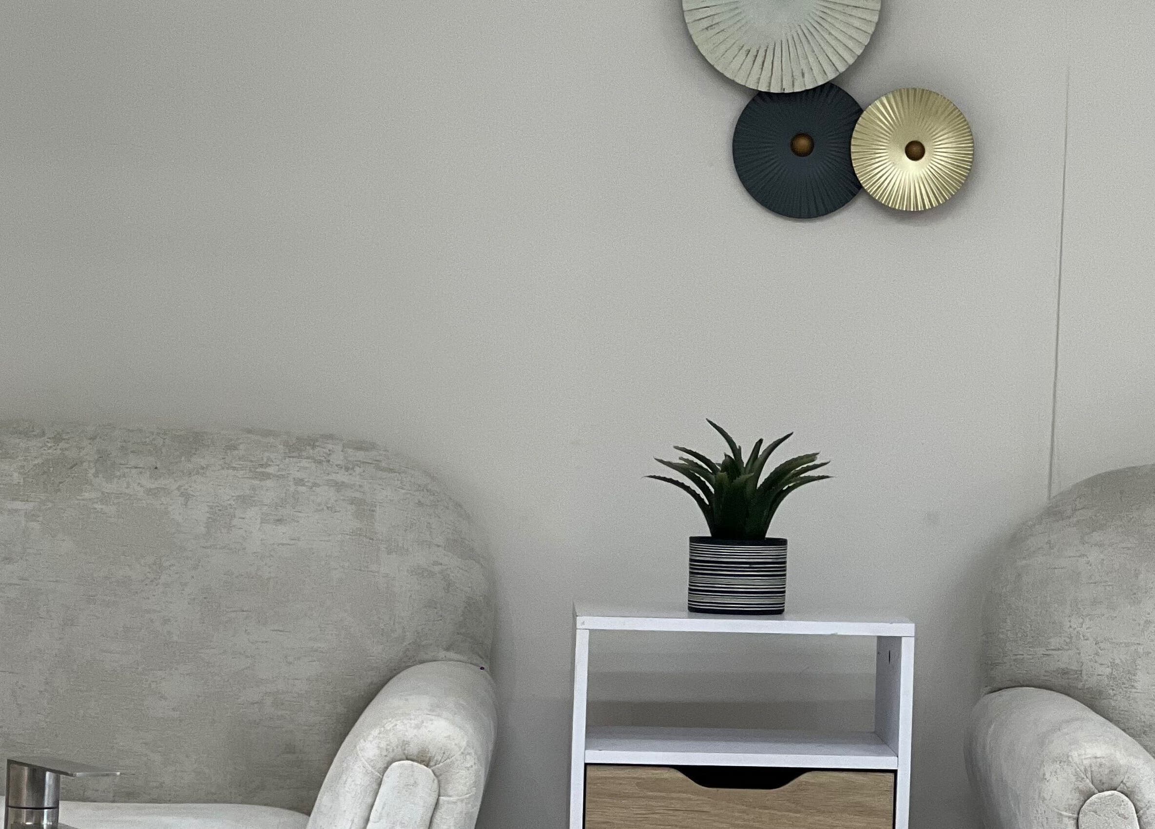 Espacio acogedor en Aura Nails Spa, Caldas, Caldas, CO, con sillones, mesa y planta decorativa.