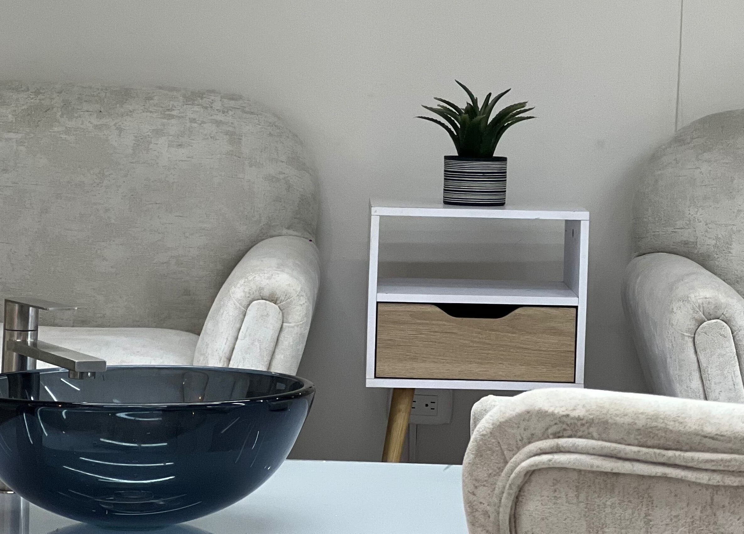 Zona de relajación en Aura Nails Spa, Caldas, Caldas, CO con sillas cómodas y elegante lavabo.