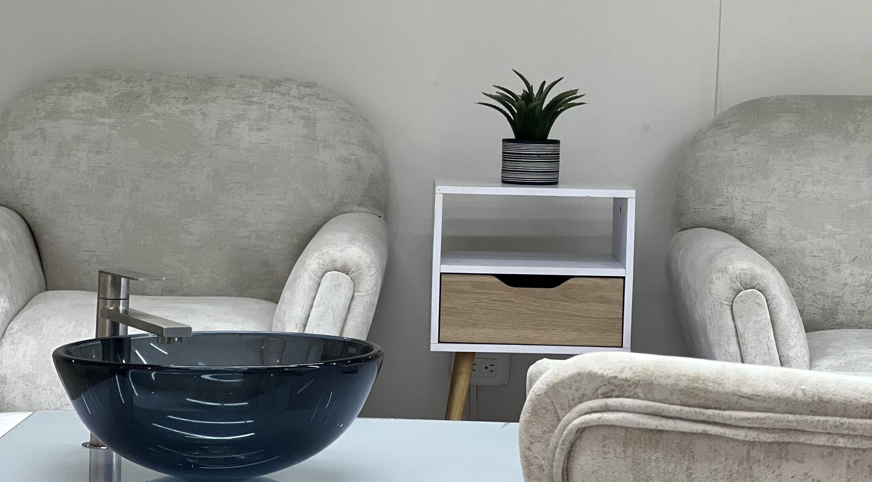 Zona de relajación en Aura Nails Spa, Caldas, Caldas, CO con sillas cómodas y elegante lavabo.