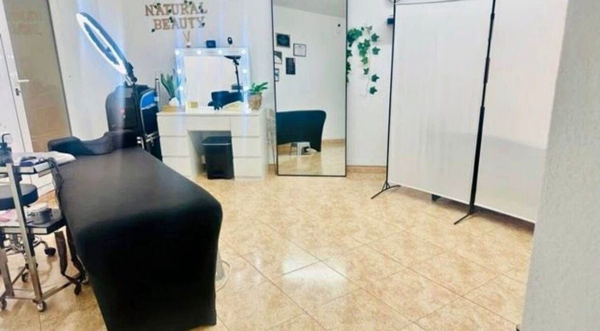 Interior del spa Paolys Hernández en Barcelona, Catalunya, ES, mostrando camilla y tocador elegante.