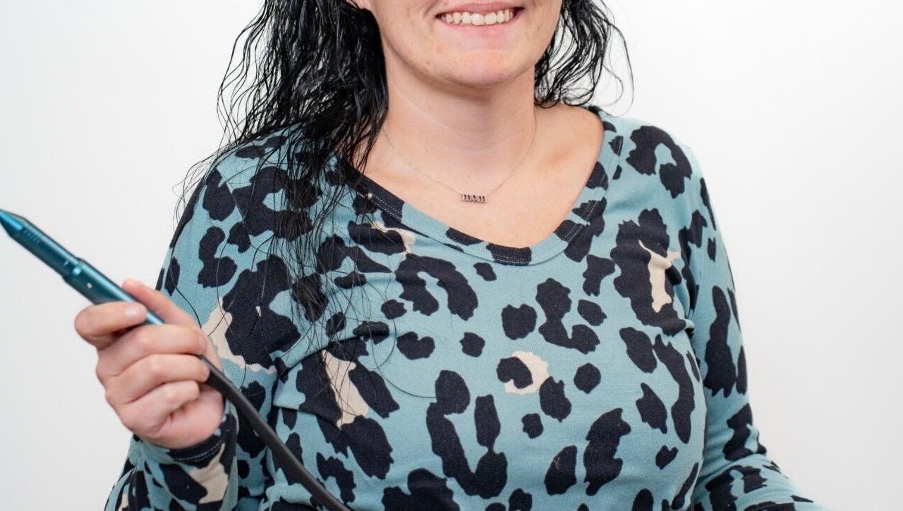 Smiling stylist holding a styling tool at Layered & Linked, Madisonville, Tennessee, US.
