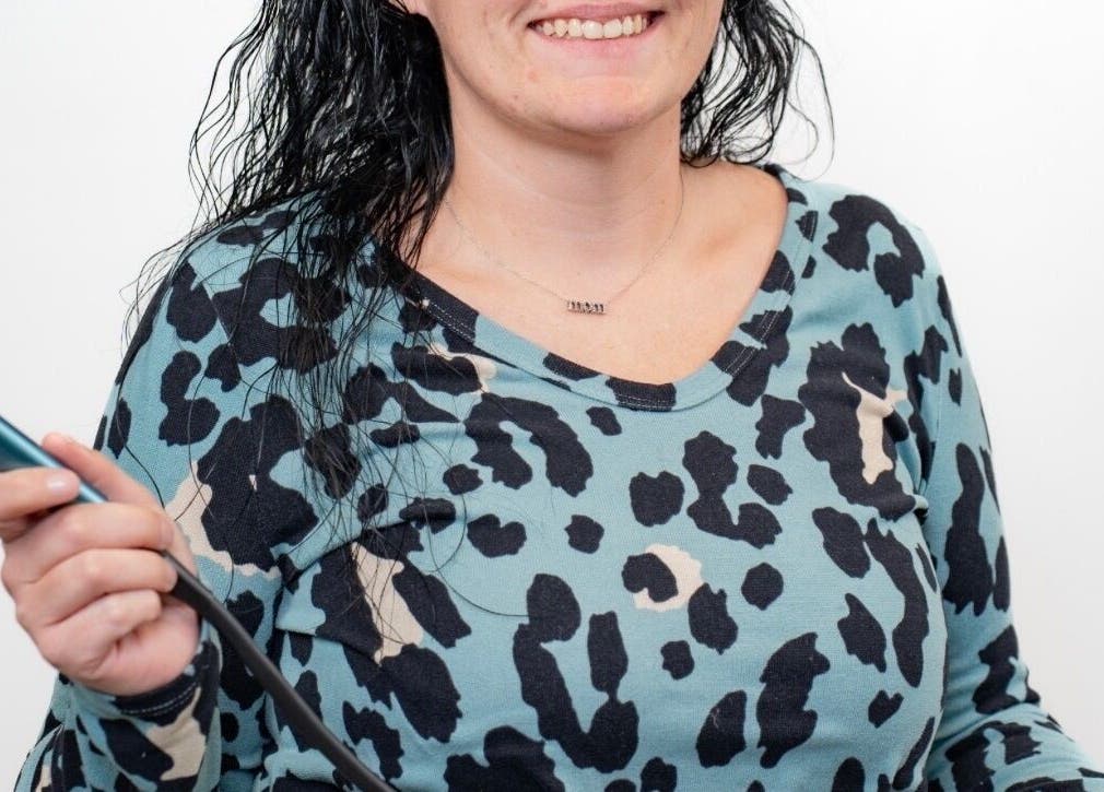 Smiling stylist holding a styling tool at Layered & Linked, Madisonville, Tennessee, US.