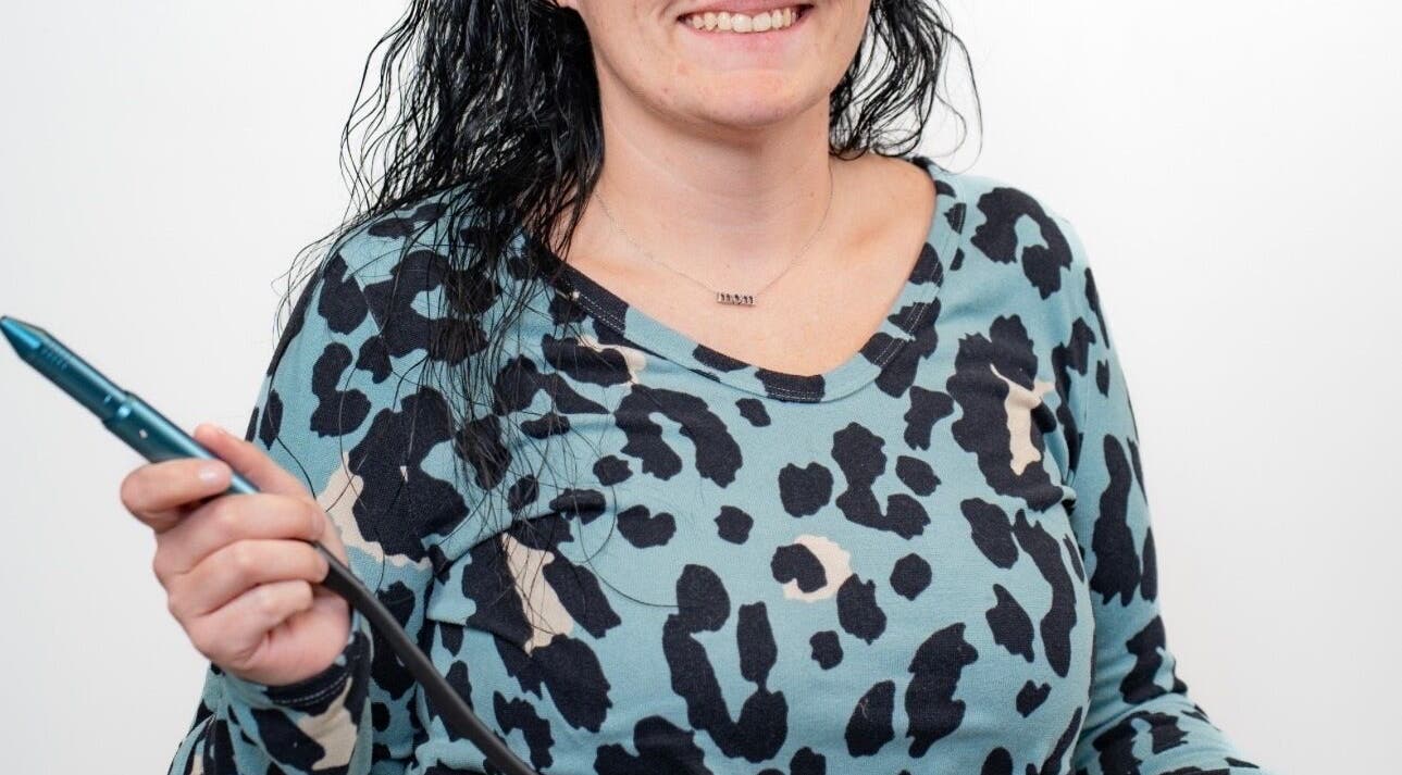 Smiling stylist holding a styling tool at Layered & Linked, Madisonville, Tennessee, US.