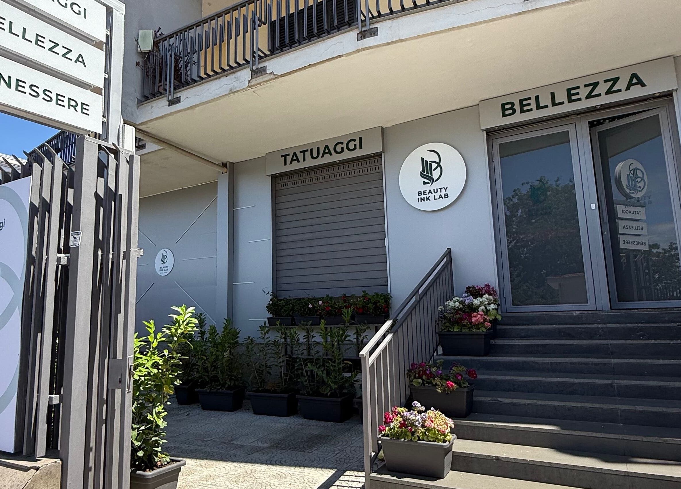 Ingresso elegante di Beauty Ink Lab a Frignano, Campania, IT con piante e cartelli di bellezza.