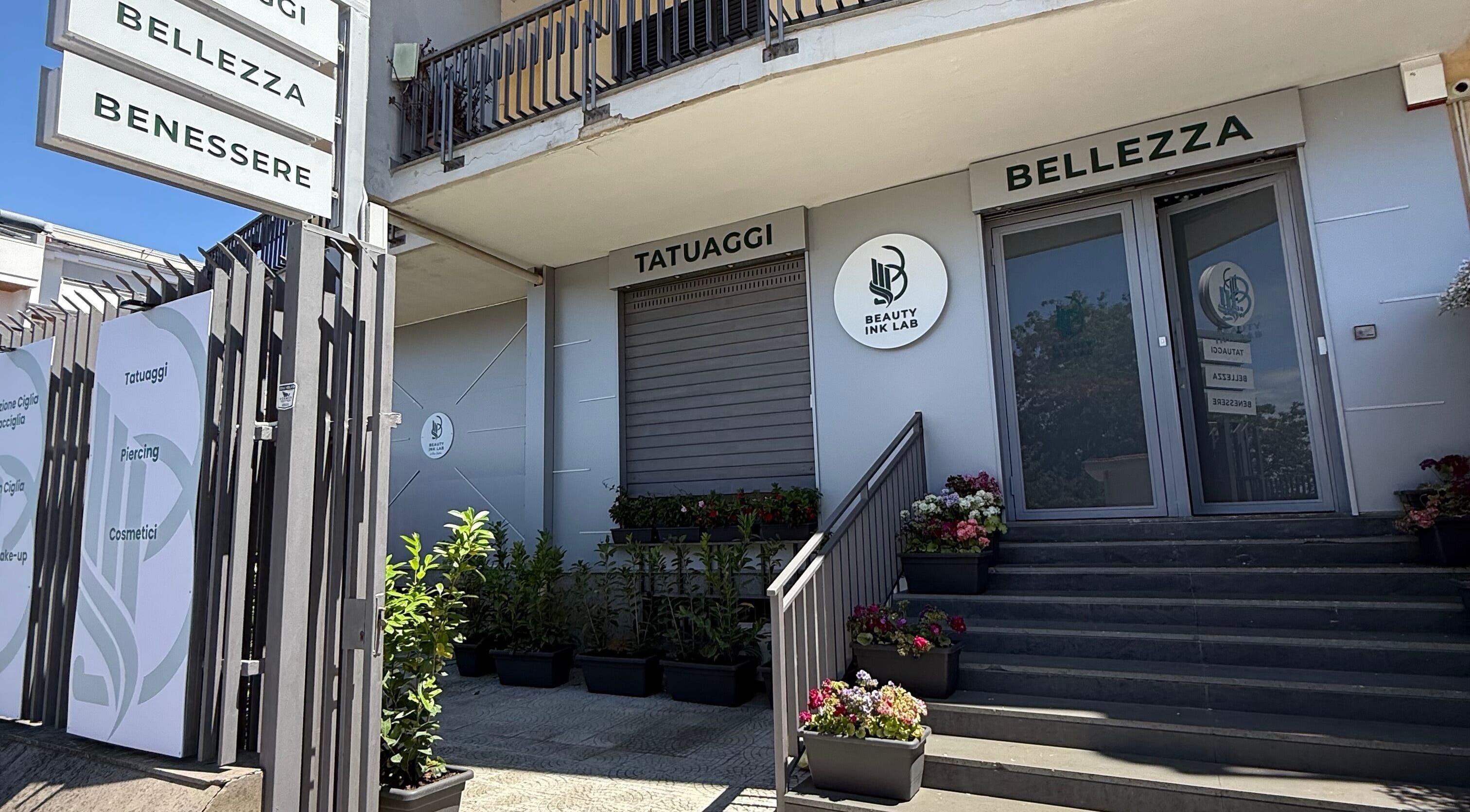 Ingresso elegante di Beauty Ink Lab a Frignano, Campania, IT con piante e cartelli di bellezza.