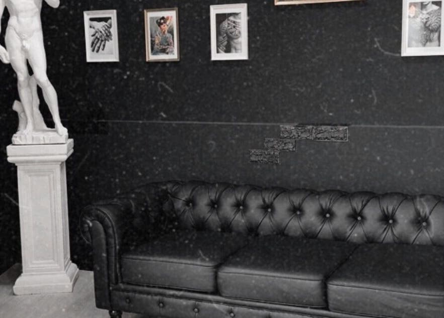Interno elegante di Got ink tattoo a Marzanello, Campania, IT con divano e statue in riflesso artistico.