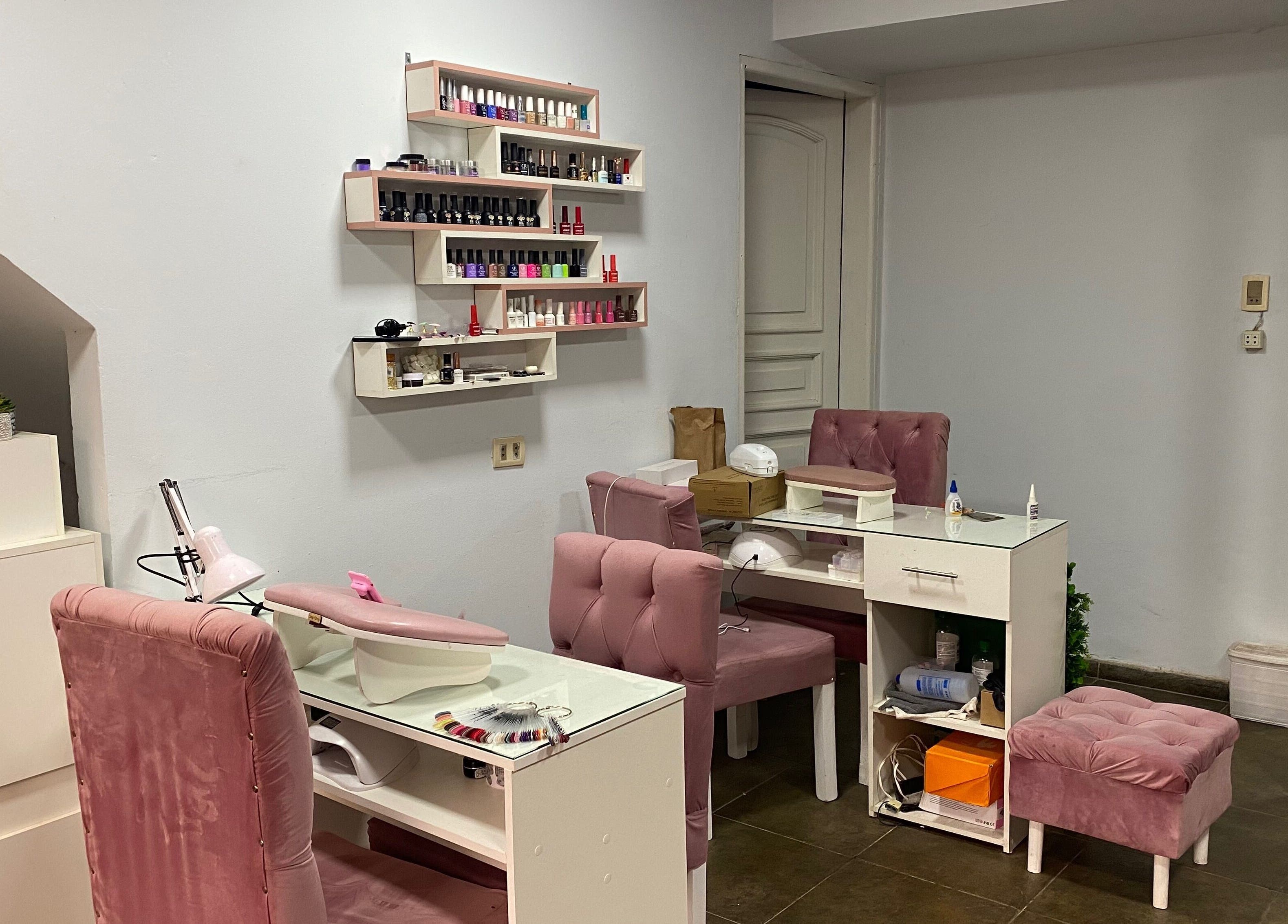 Chic nail salon setup at Sibaris, Luque, Central, PY featuring plush pink chairs and organized nail polish racks.