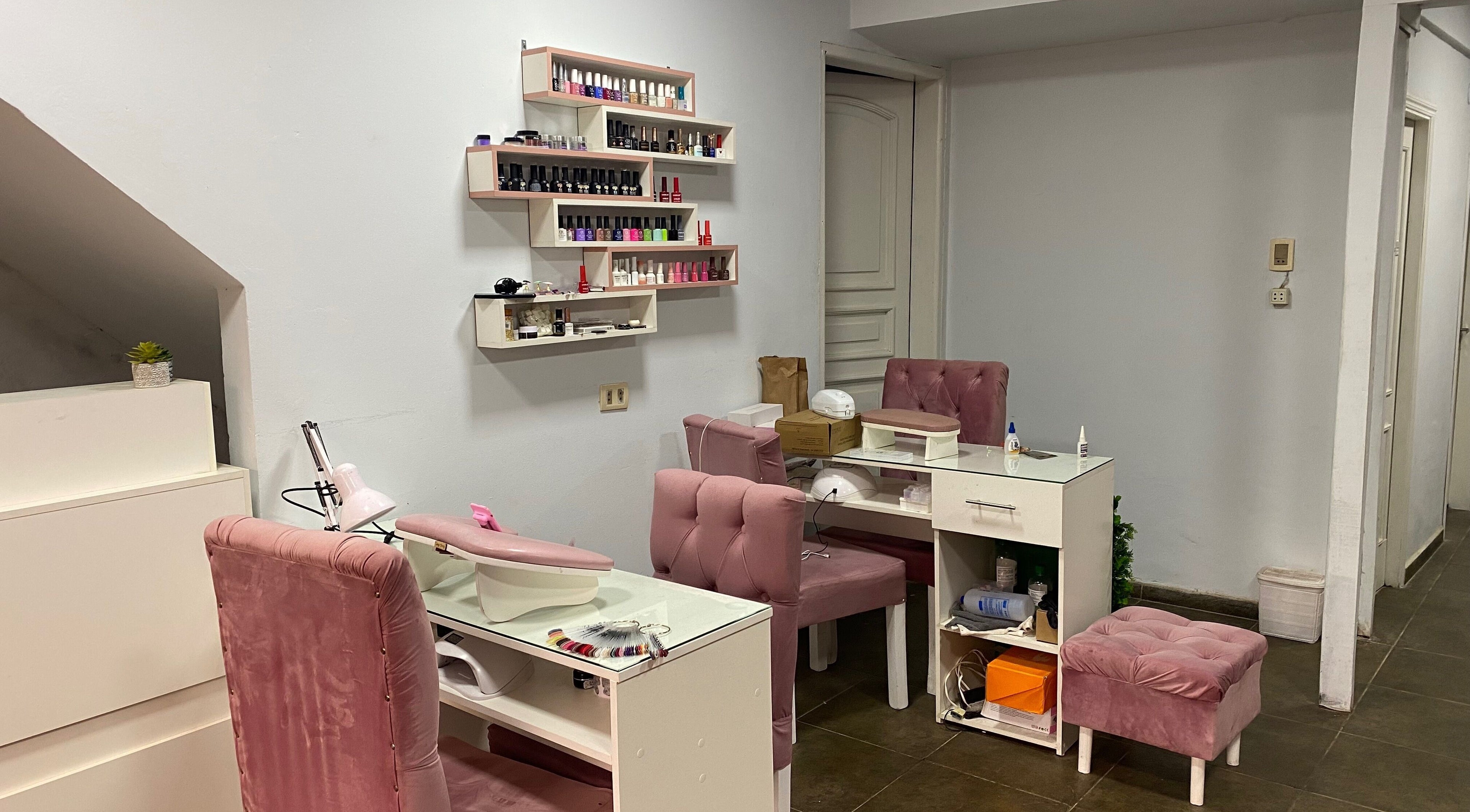 Chic nail salon setup at Sibaris, Luque, Central, PY featuring plush pink chairs and organized nail polish racks.
