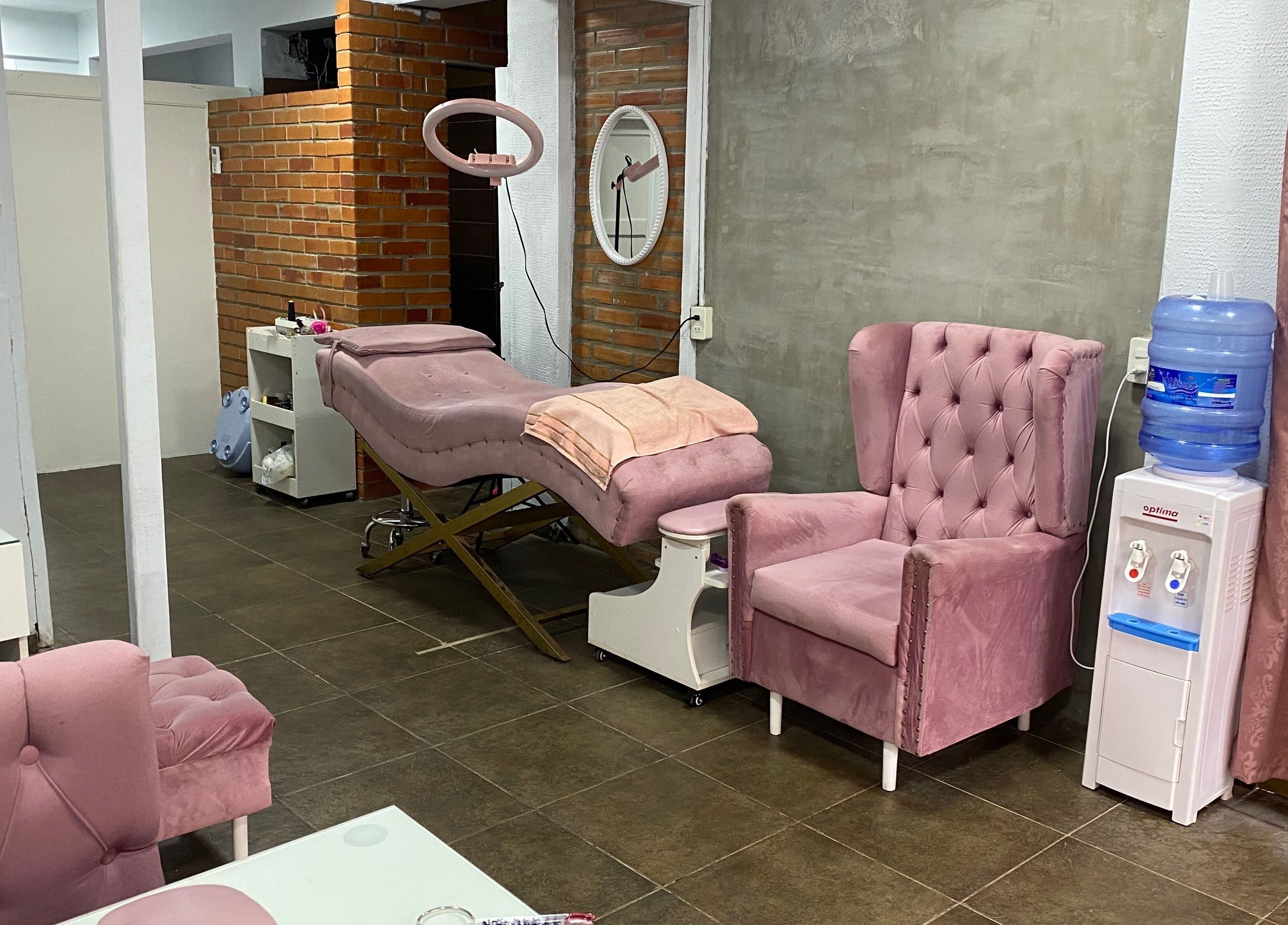 Pink therapy room at Sibaris in Luque, Central, PY with plush chairs and aesthetic treatment bed.