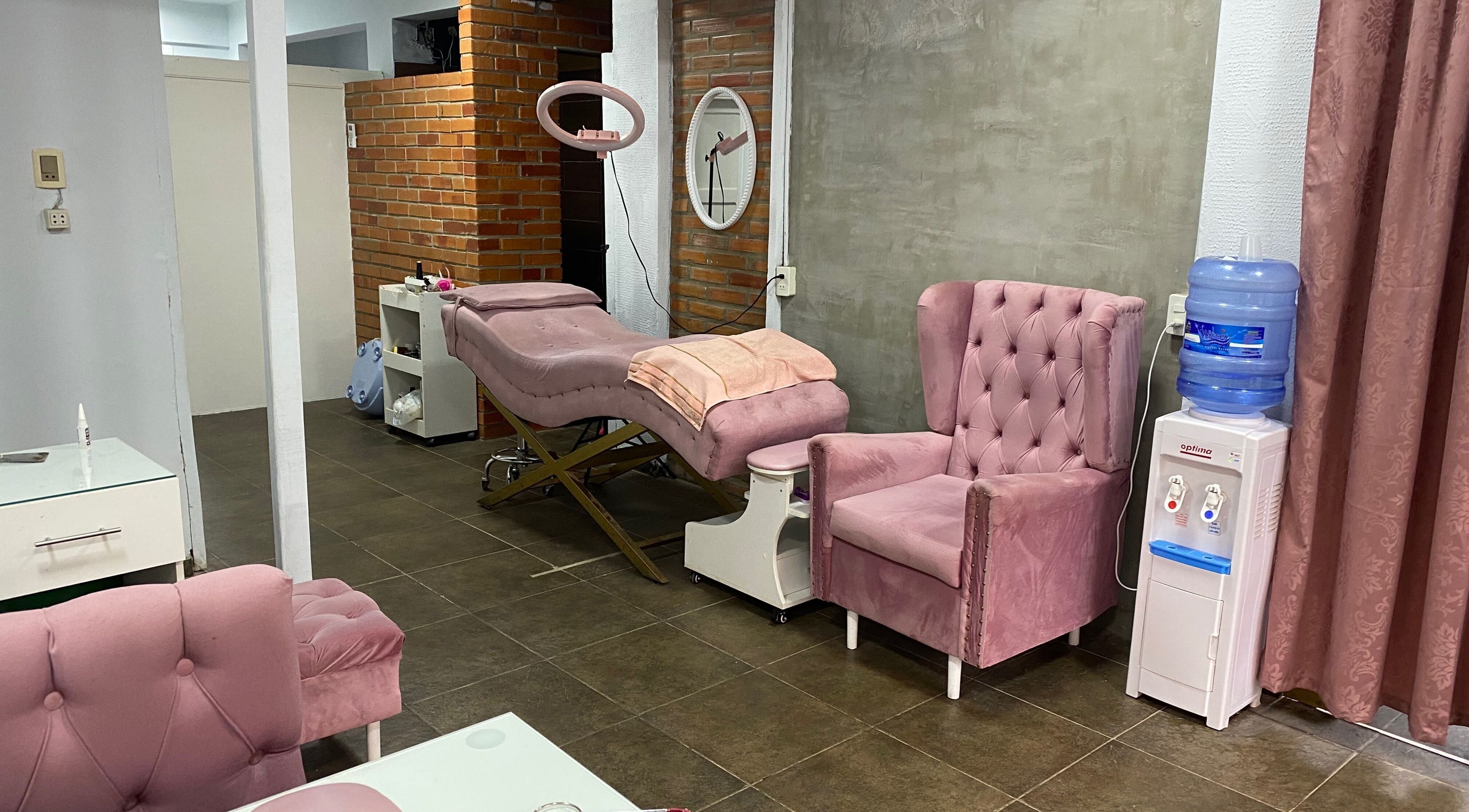 Pink therapy room at Sibaris in Luque, Central, PY with plush chairs and aesthetic treatment bed.