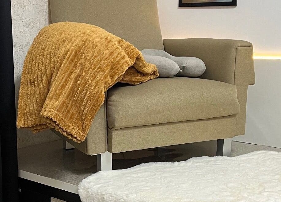 Poltrona confortável com manta dourada no Aura Private Nail Suite, Camarate, Lisboa, PT.