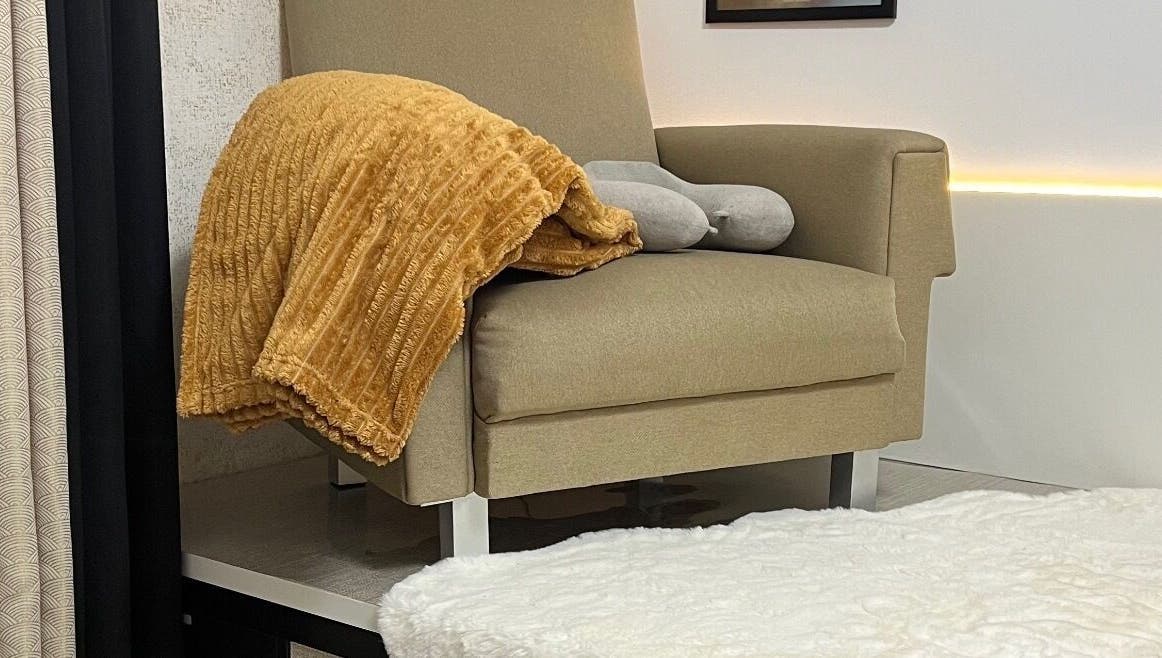 Poltrona acolhedora em Aura Private Nail Suite, Camarate, Lisboa, PT, com manta laranja e decoração elegante.