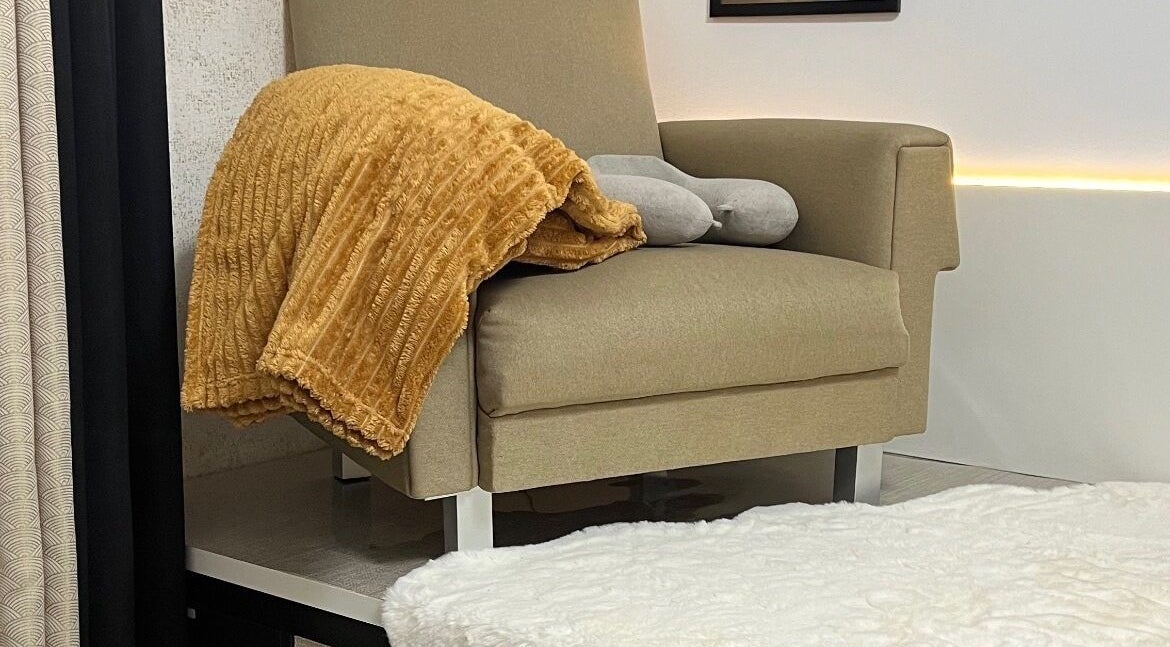 Poltrona acolhedora em Aura Private Nail Suite, Camarate, Lisboa, PT, com manta laranja e decoração elegante.