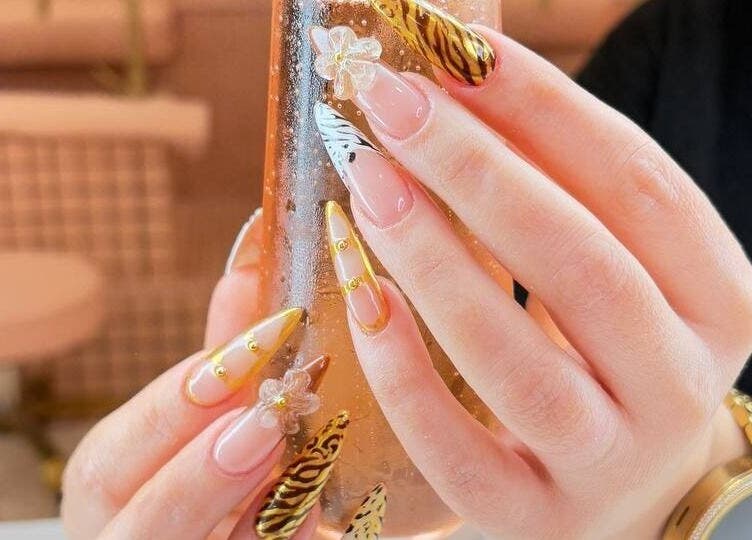 Intricate nail art at Hadis nail in Sydney, New South Wales, AU showcases gold and zebra patterns with floral details.