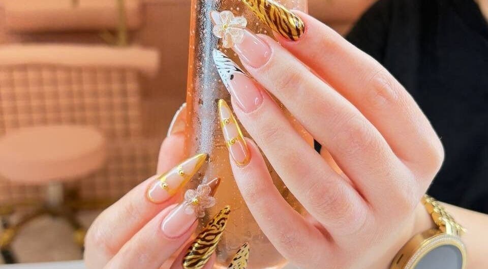 Intricate nail art at Hadis nail in Sydney, New South Wales, AU showcases gold and zebra patterns with floral details.