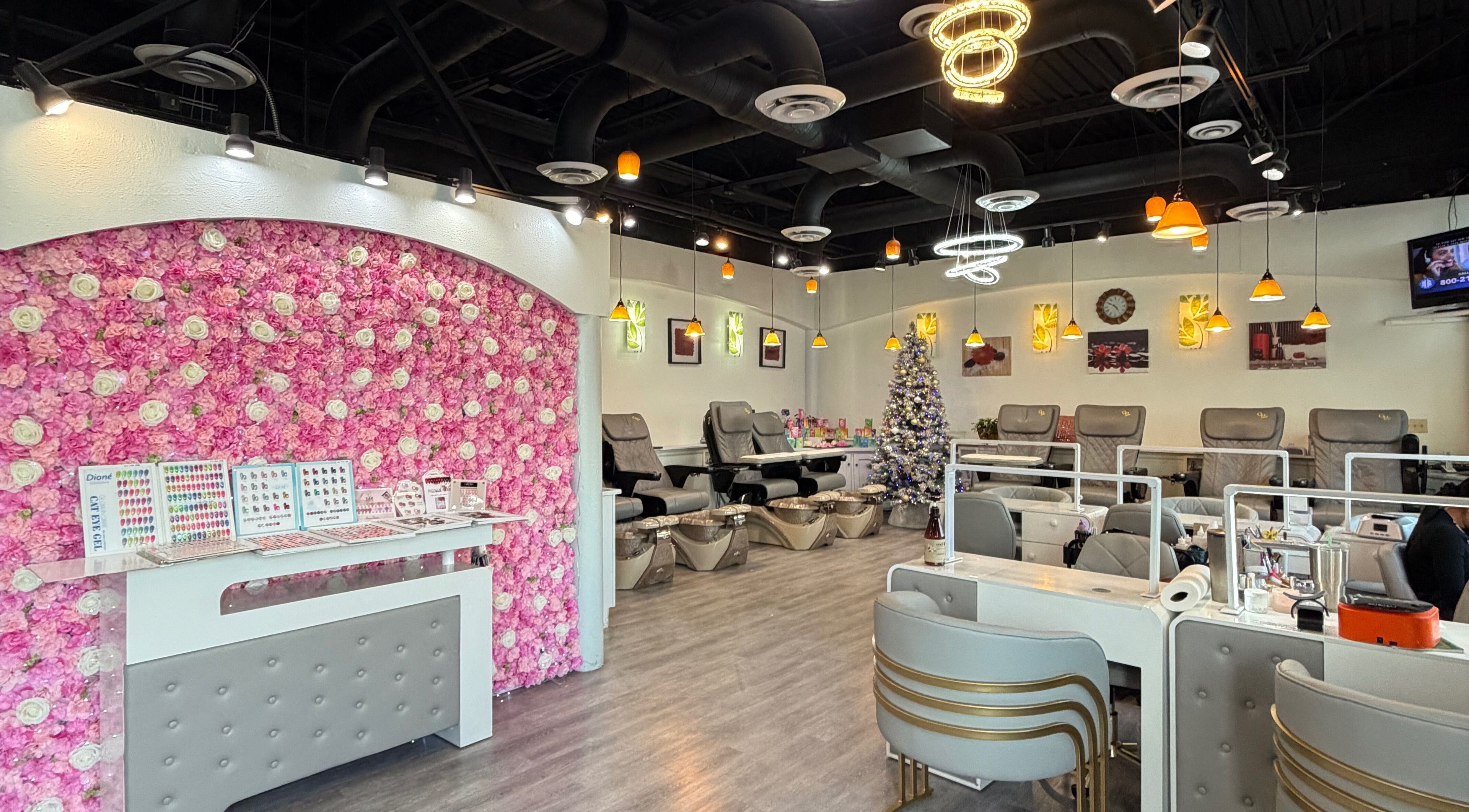 Bright Da Vi Nails interior in San Antonio, Texas, US with pink floral wall and nail stations.